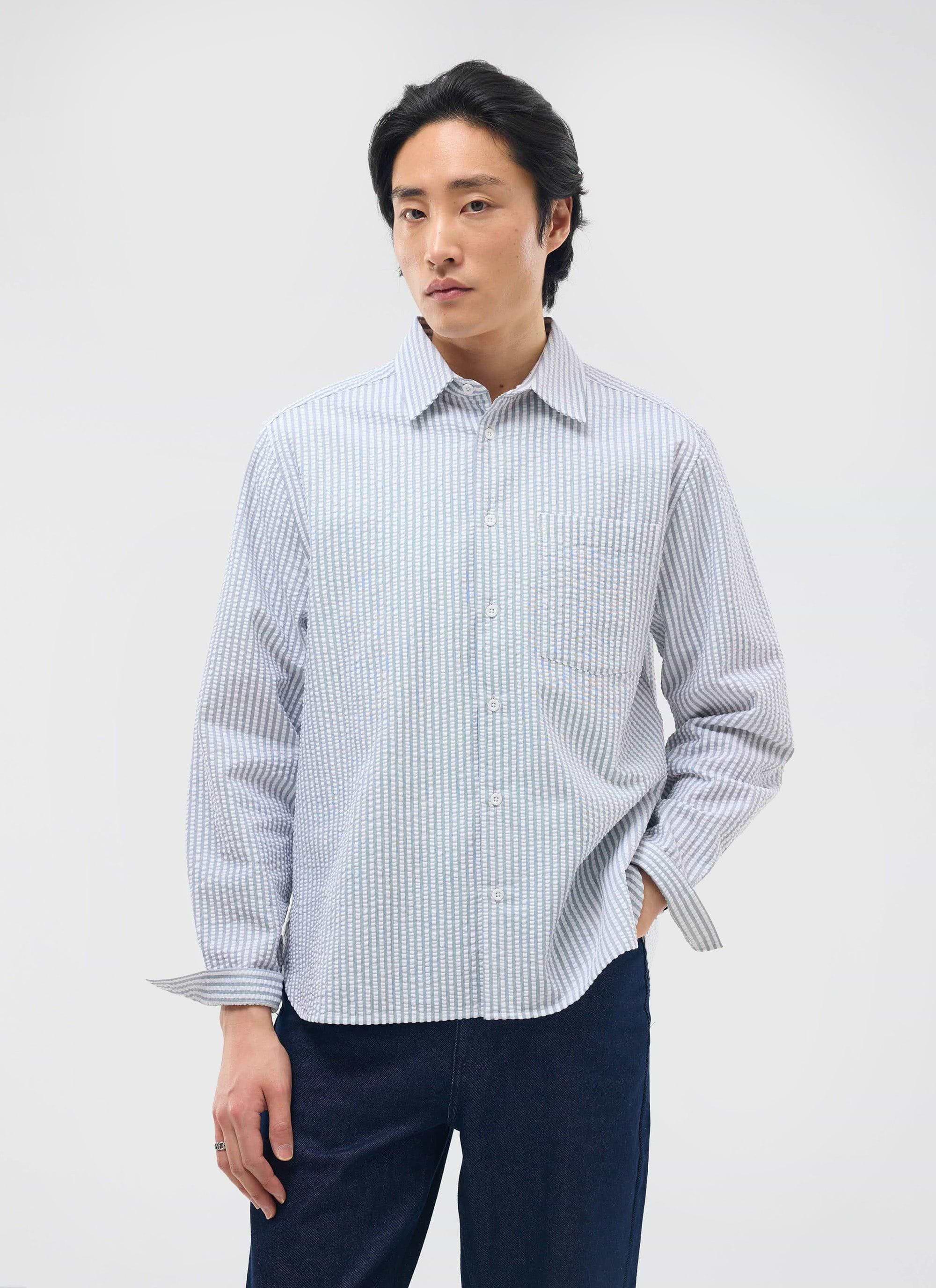 A model wears the Percival Seersucker Stripe Pearce Shirt in grey, paired with dark trousers against a white background.