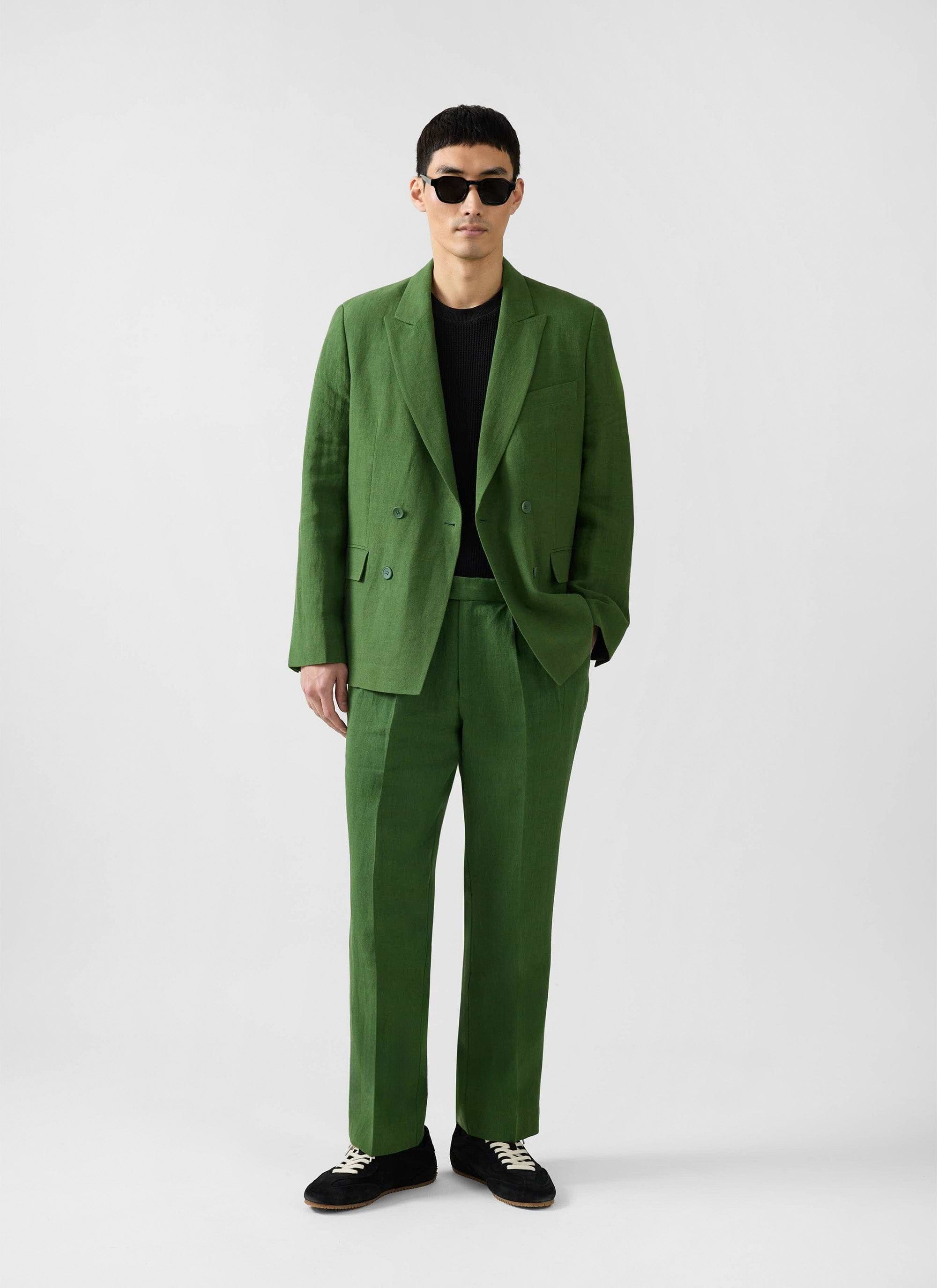 A man models the Percival Clifton Double Breasted Blazer in forest green linen, paired with matching trousers.