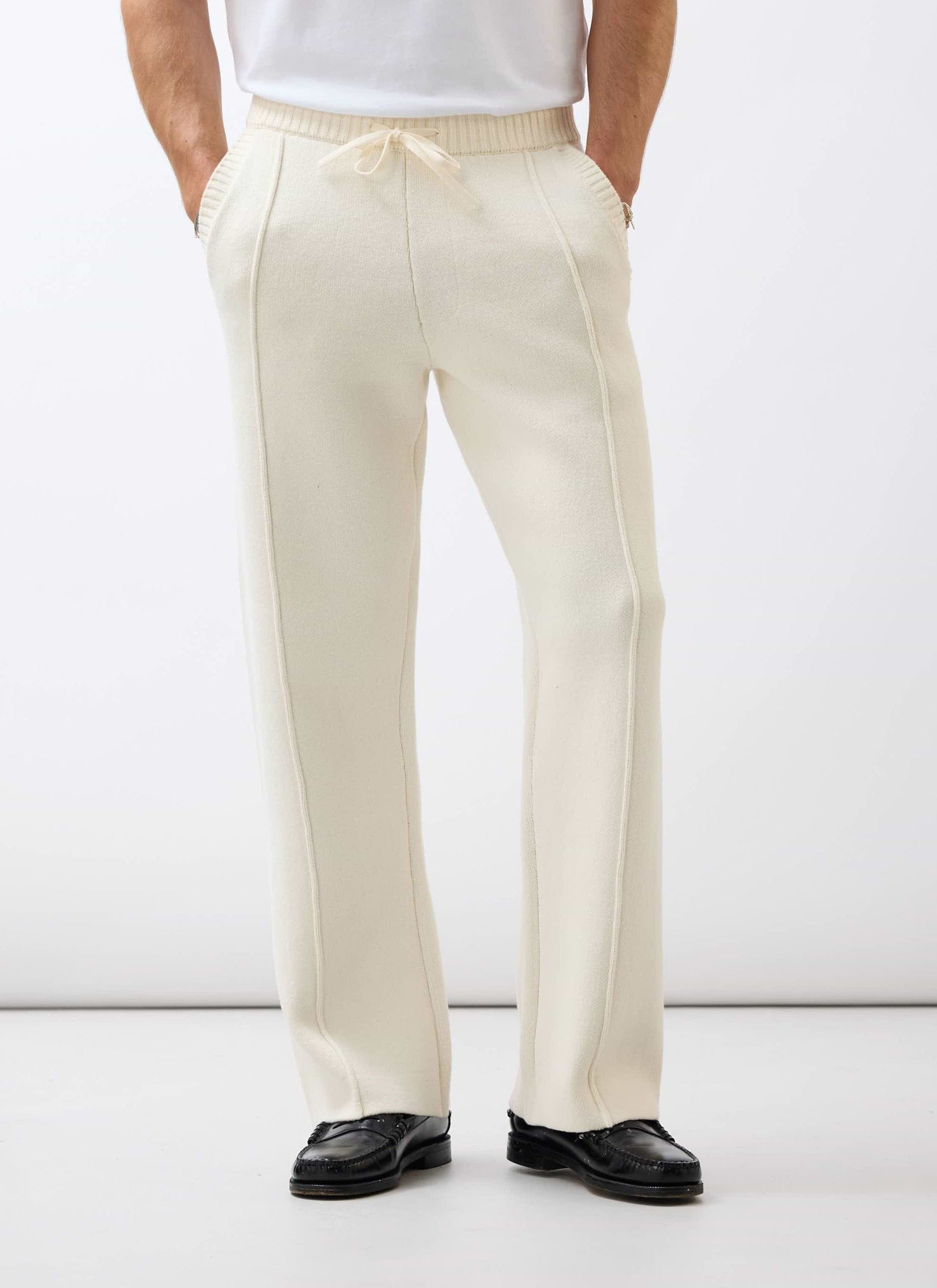 A model wears the Percival Chronicle Knitted Straight Leg Trackpant in ecru cotton, paired with smart black loafers.