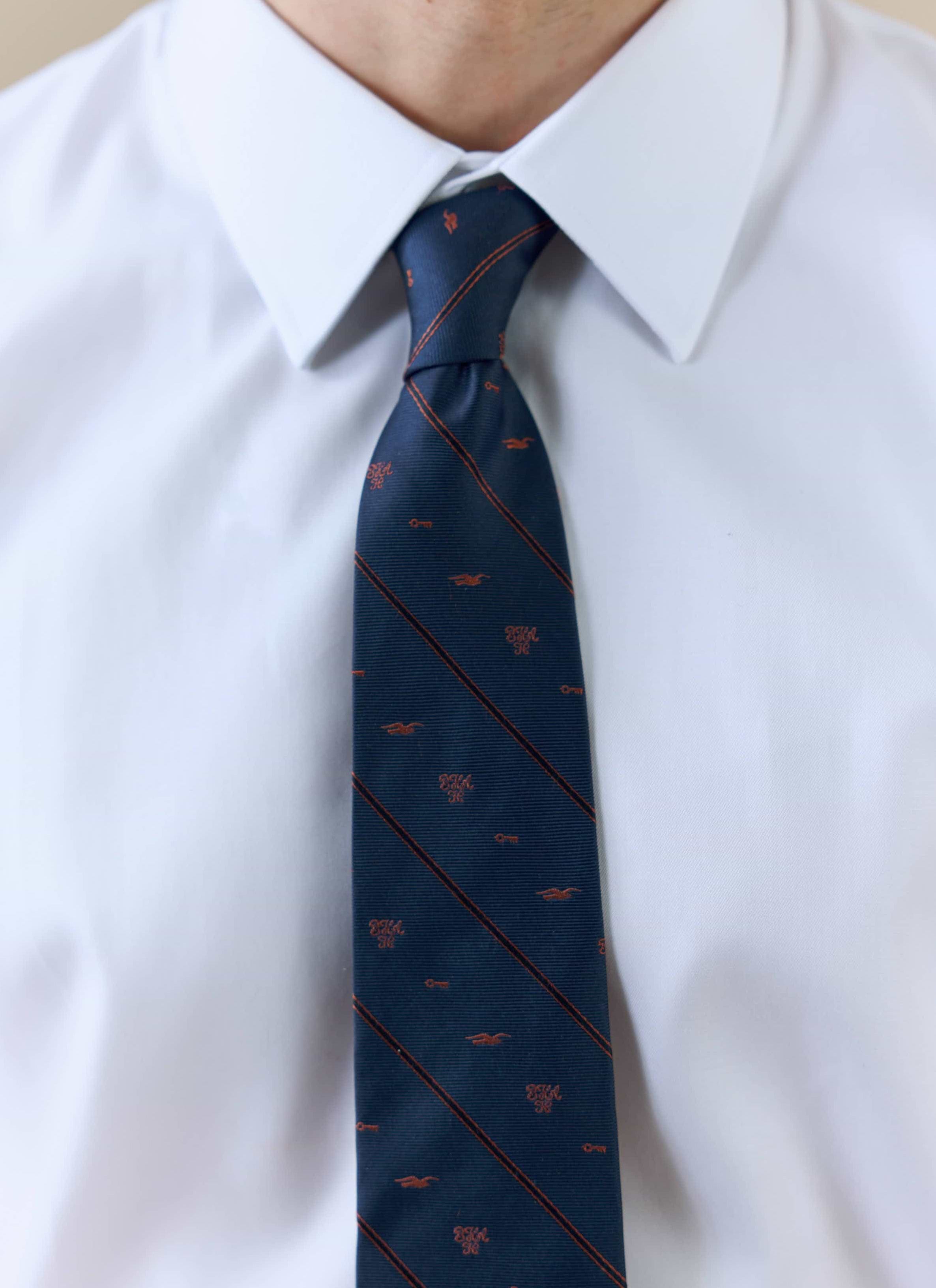 A close-up of a model wearing the Percival x Brighton & Hove Albion F.C. navy silk jacquard tie, showing the stripe pattern.