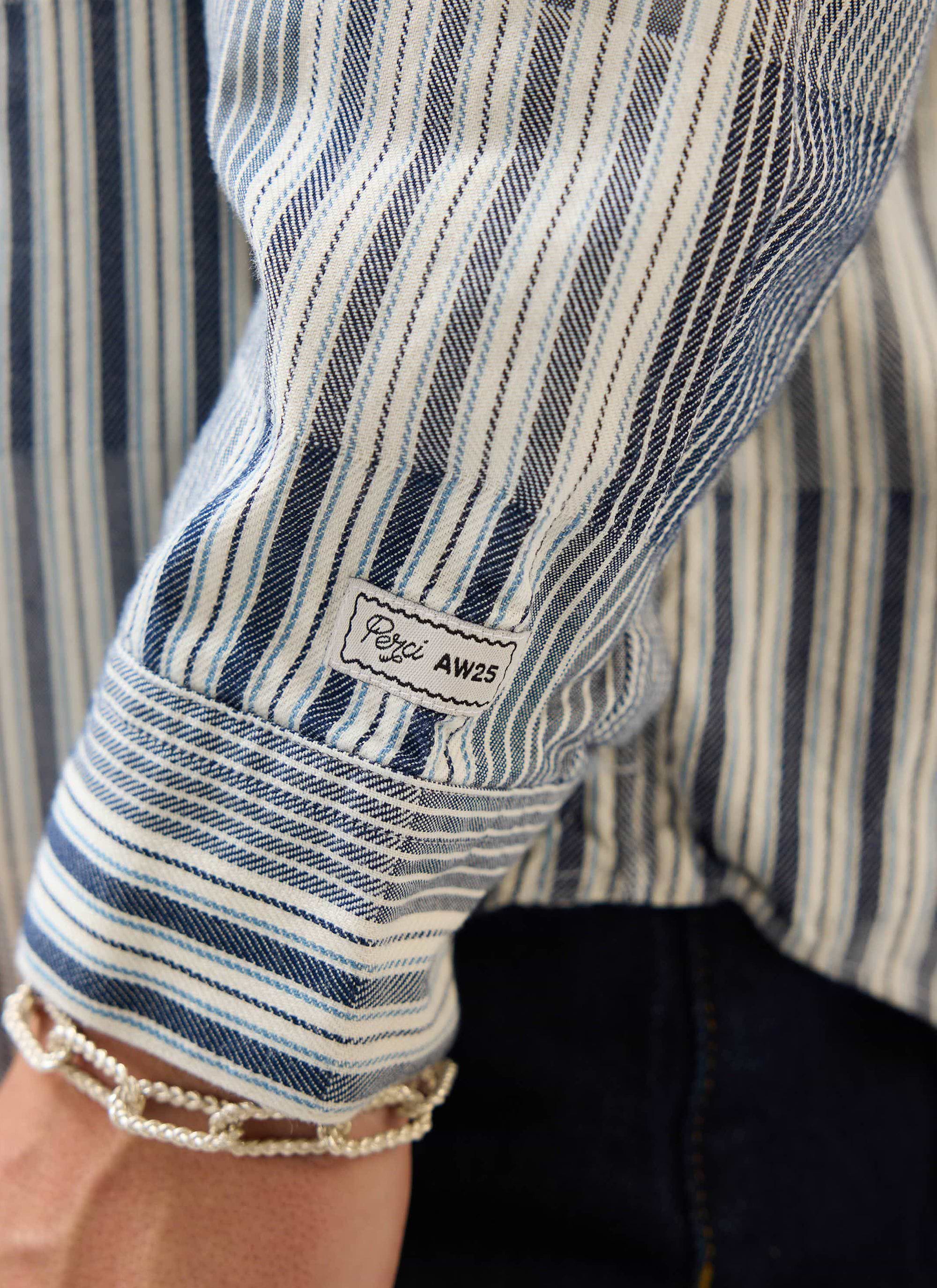 A close-up of the patchwork jacquard cuff and sleeve of the blue Epigraph Pearce Shirt from Percival with brand label detail.