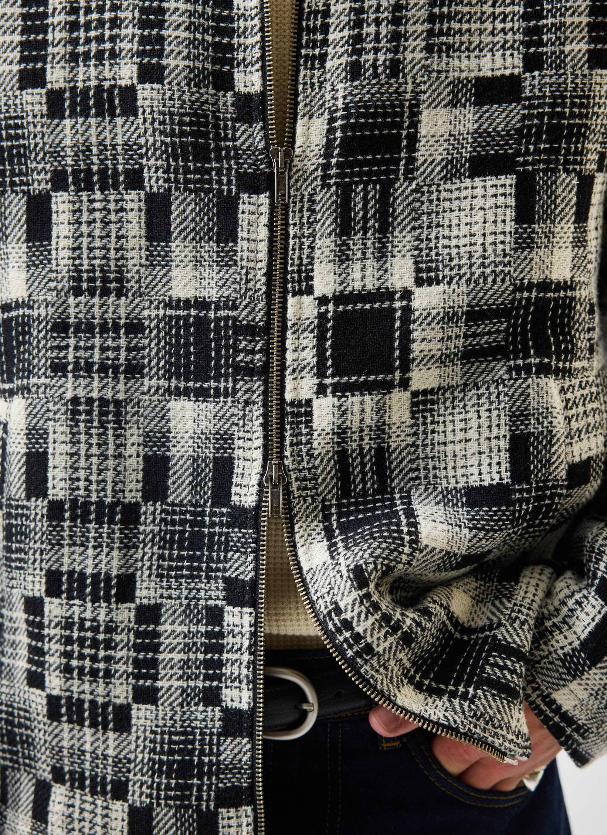 A close-up of the Percival Men's Glossary Patchwork Jacket in grey, showing the textured twill fabric and two-way zip.