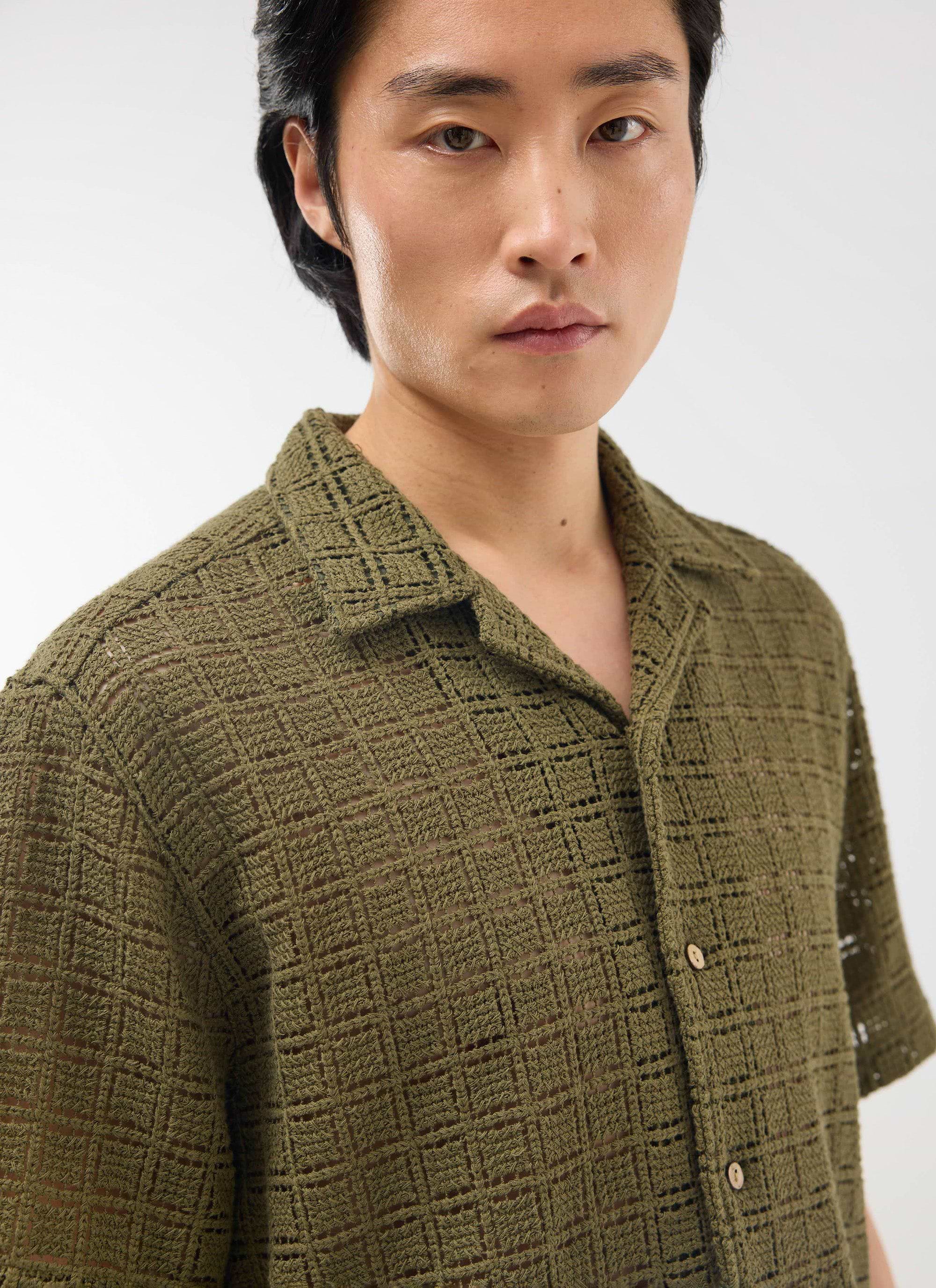 A studio close-up of a model wearing the Percival Palermo Crochet Cuban Shirt in olive green, showing the intricate fabric.