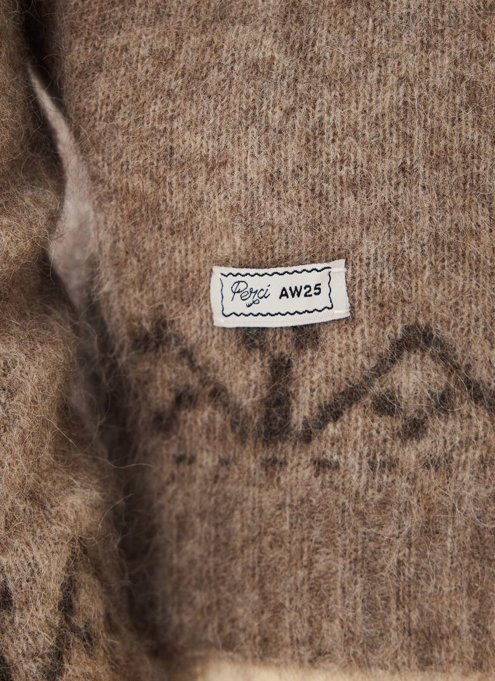 A close-up of the internal Percival AW25 collection label on the soft, oak-coloured wool blend Novel Collared Cardigan.