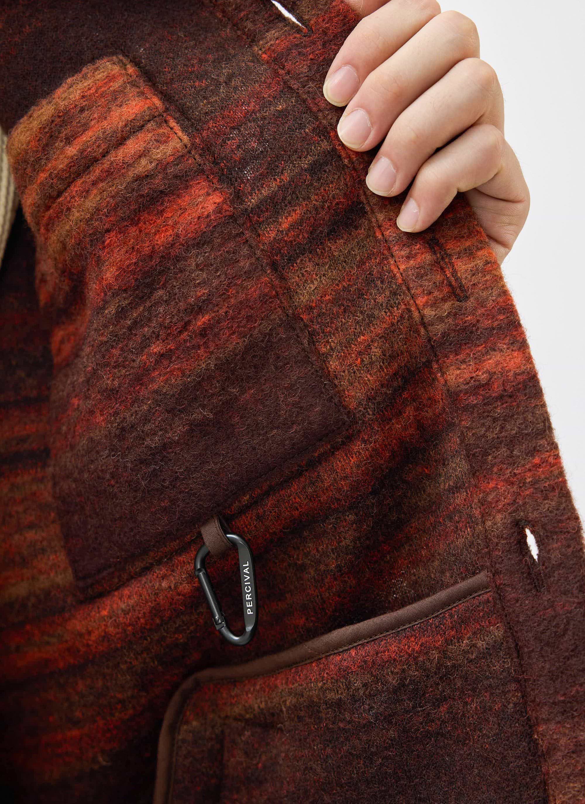Close-up of the Mississippi Jacquard Overshirt's inner pocket in burnt orange boiled wool, with a black Percival carabiner.