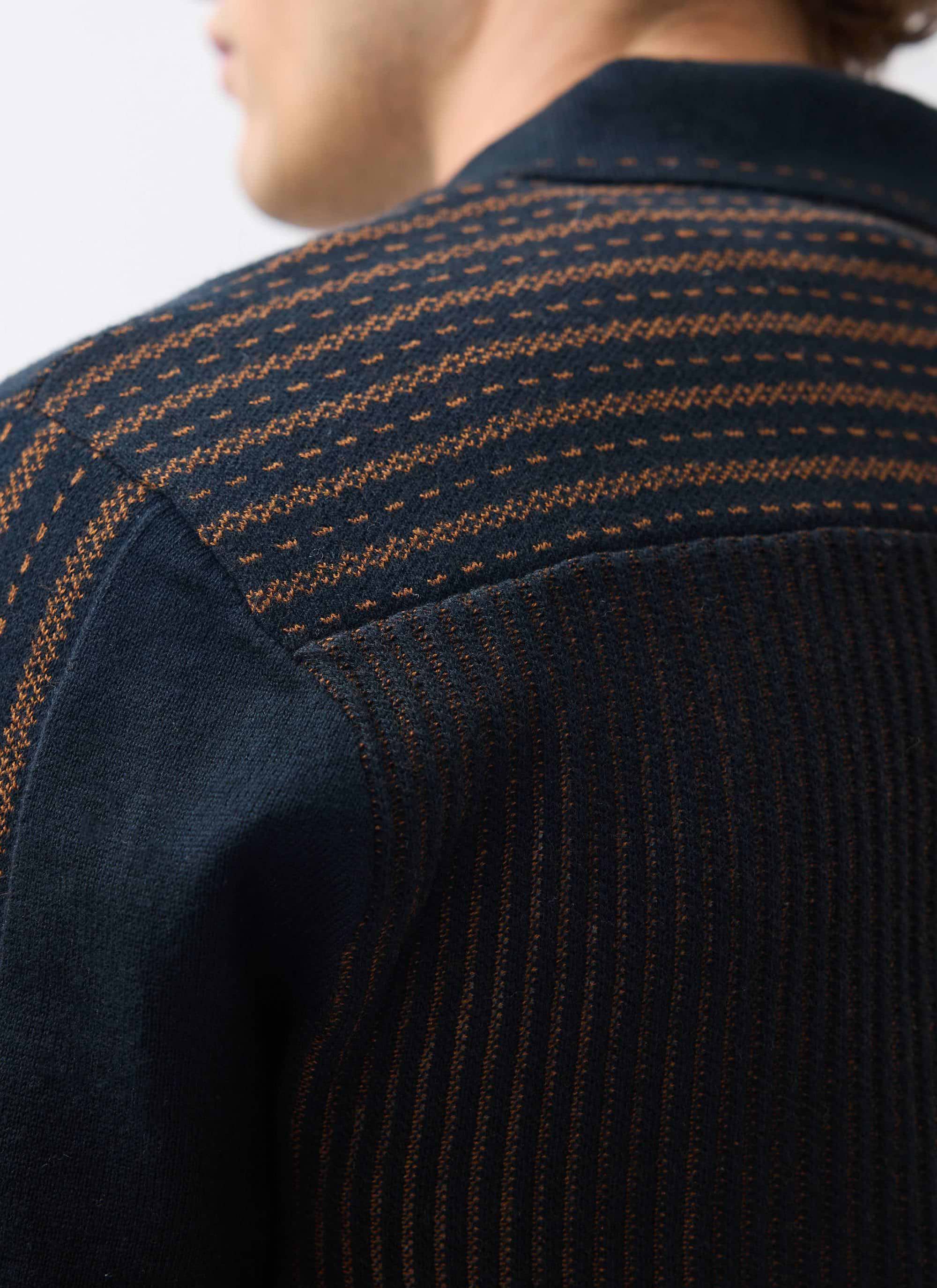 A close-up view of the intricate brown jacquard knit pattern on the shoulder of the black Percival Appendix Knitted Shirt.