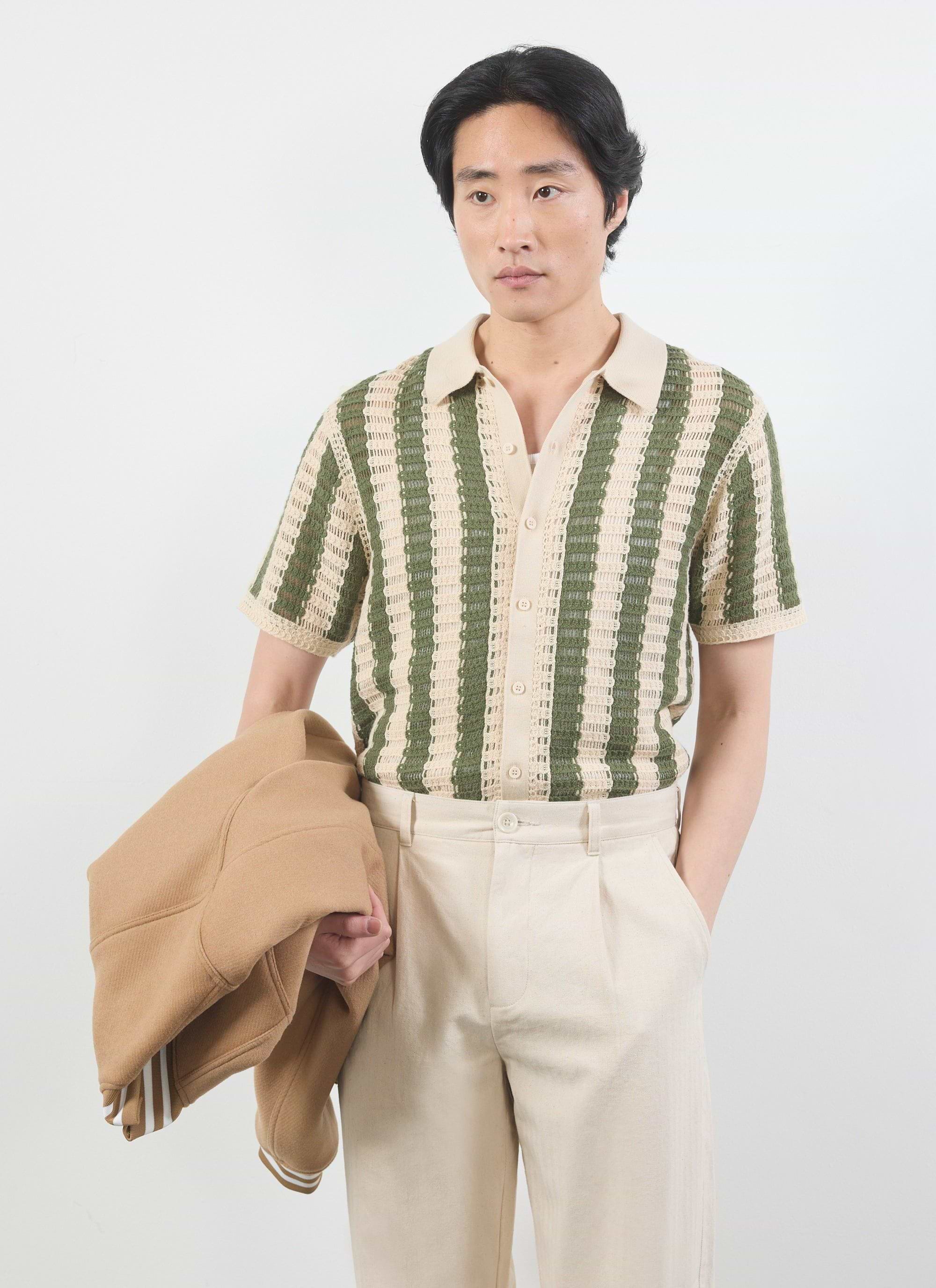 The Percival Barletta Knitted Shirt in olive, a striped crochet top, styled on a model with cream trousers and a tan jacket.