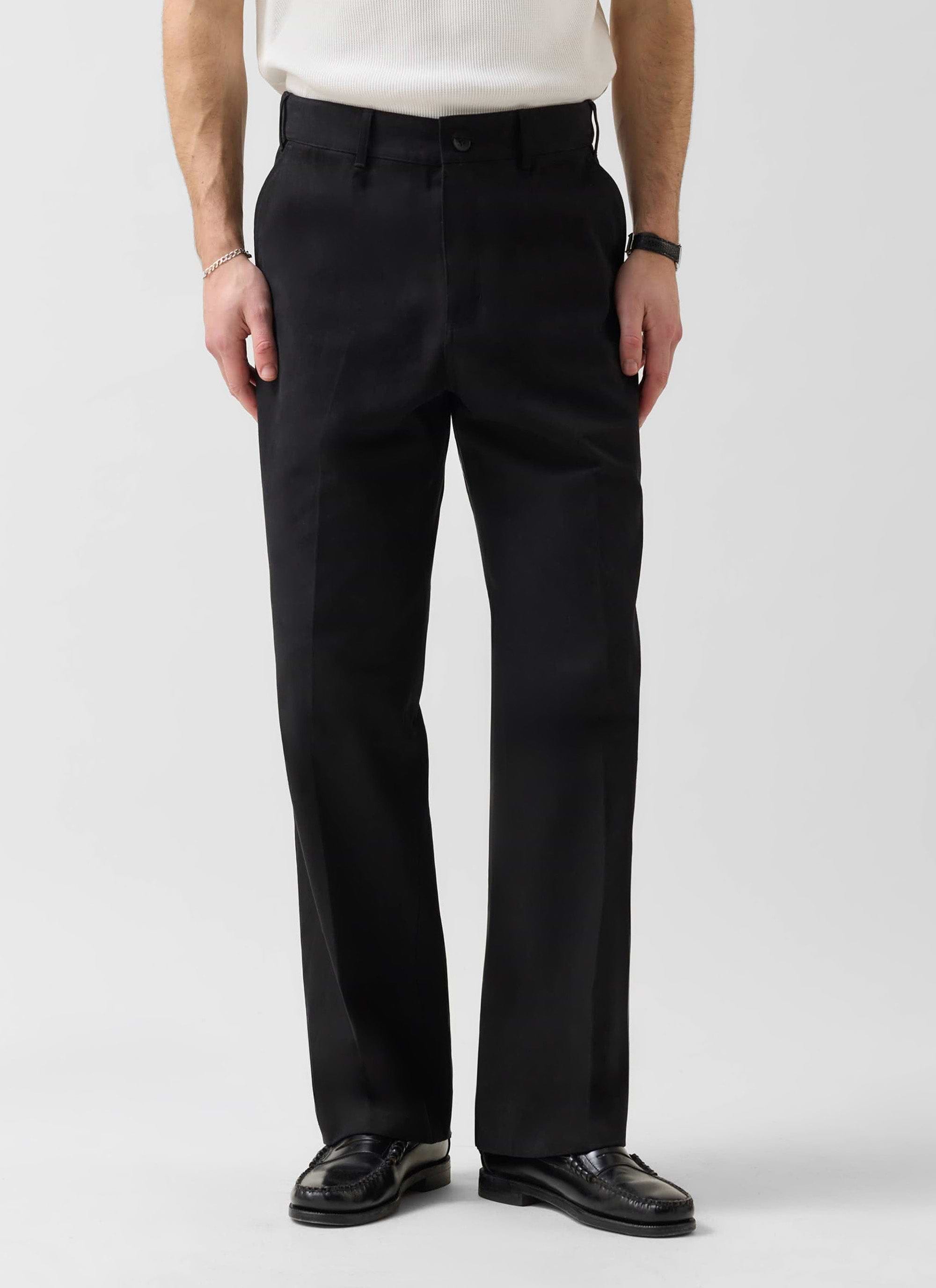 A man models the black cotton Wide Leg Chino from Percival, paired with black loafers against a clean white background.