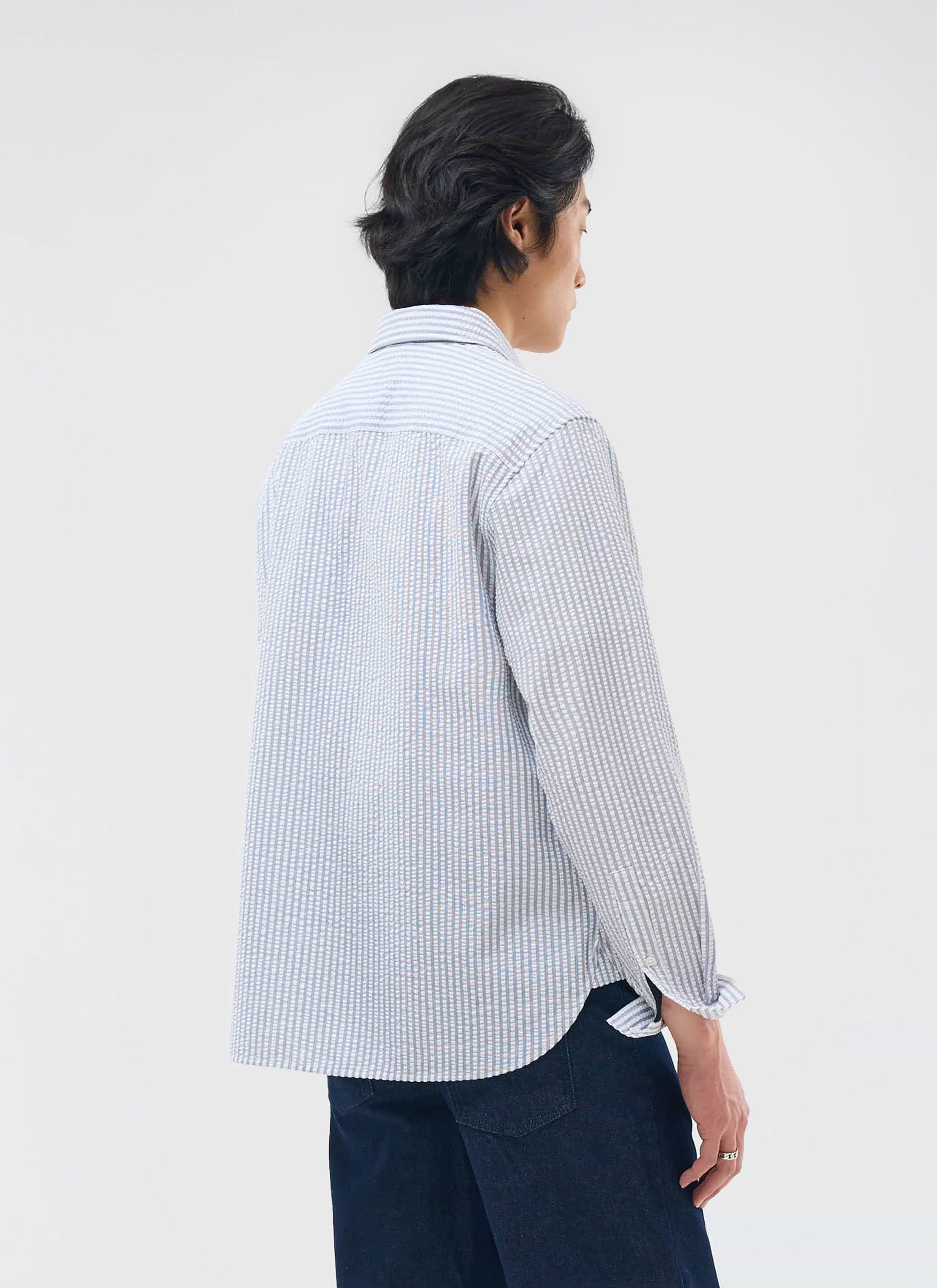 A model shows the back of the grey and ecru Percival Seersucker Stripe Pearce Shirt, showing its textured, oversized fit.