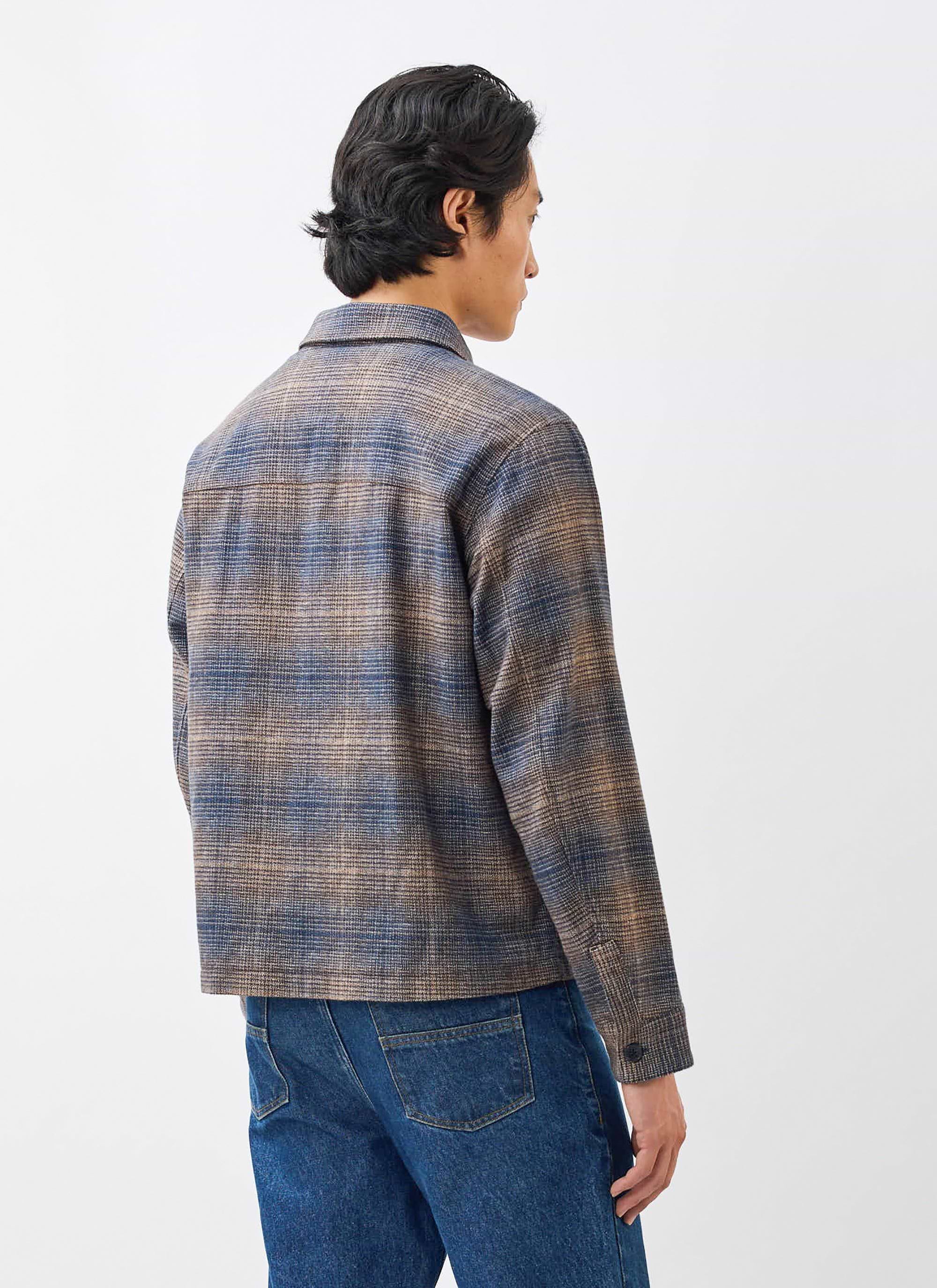 A model seen from behind, wearing the Luton Check Overshirt in brown and blue by Percival with a pair of blue jeans.