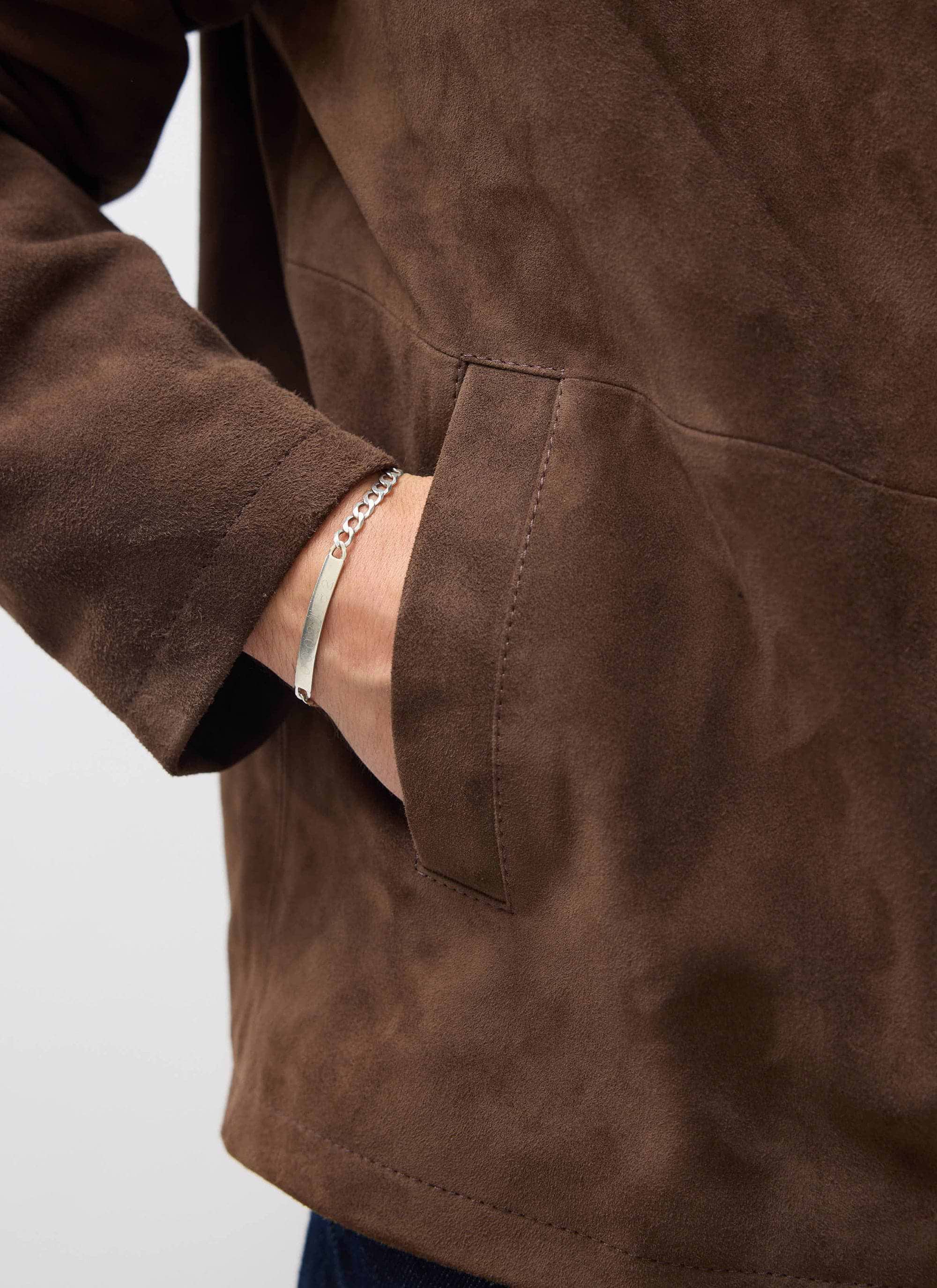 A close-up of the soft suede texture and pocket of the Percival Prologue Jacket in Espresso Brown.