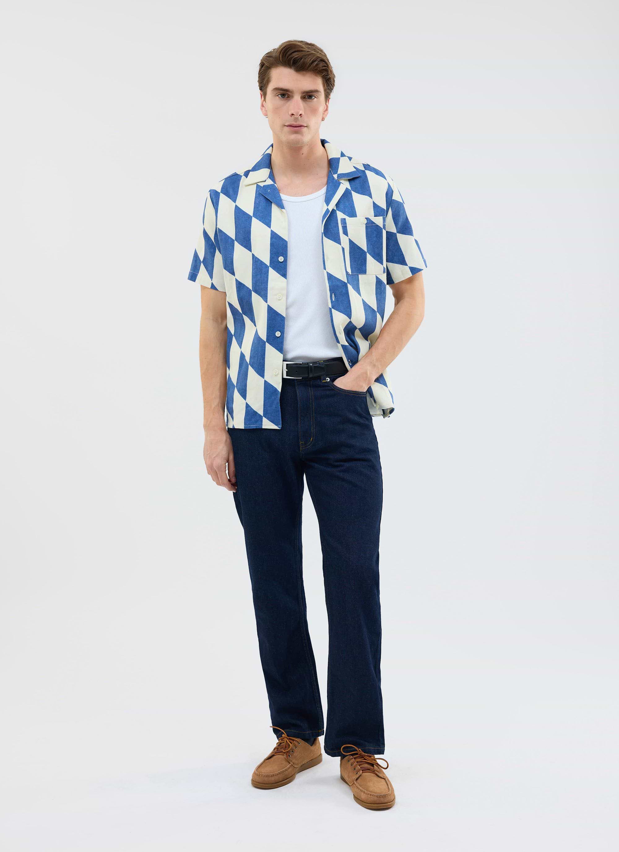 A model wears the Percival Market Diamond Cuban Shirt in ecru and navy, styled with dark jeans and a white t-shirt.