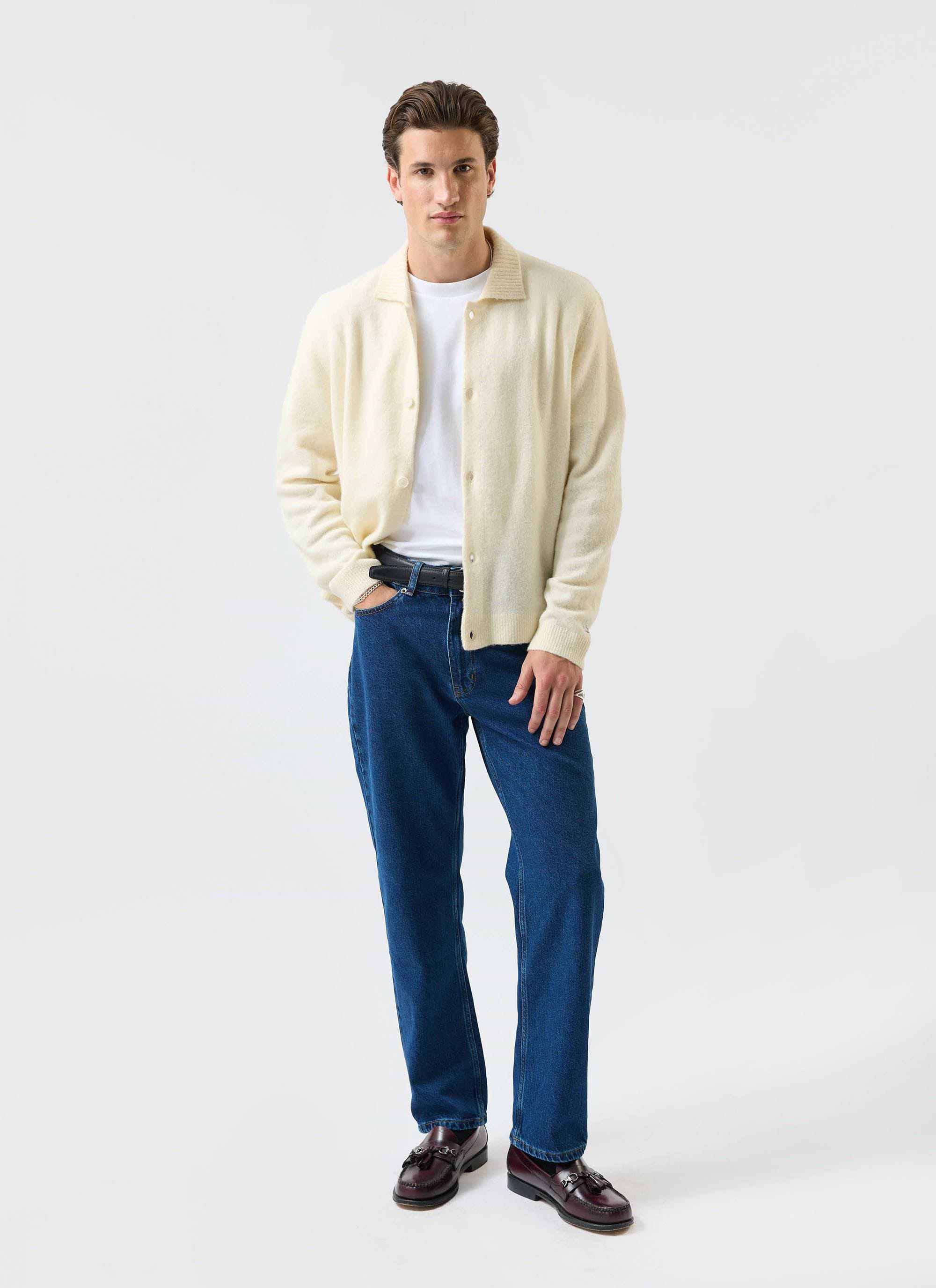 A model wears the Percival Archive Wool Collared Cardigan in ecru cream, styled with a white t-shirt and dark blue jeans.