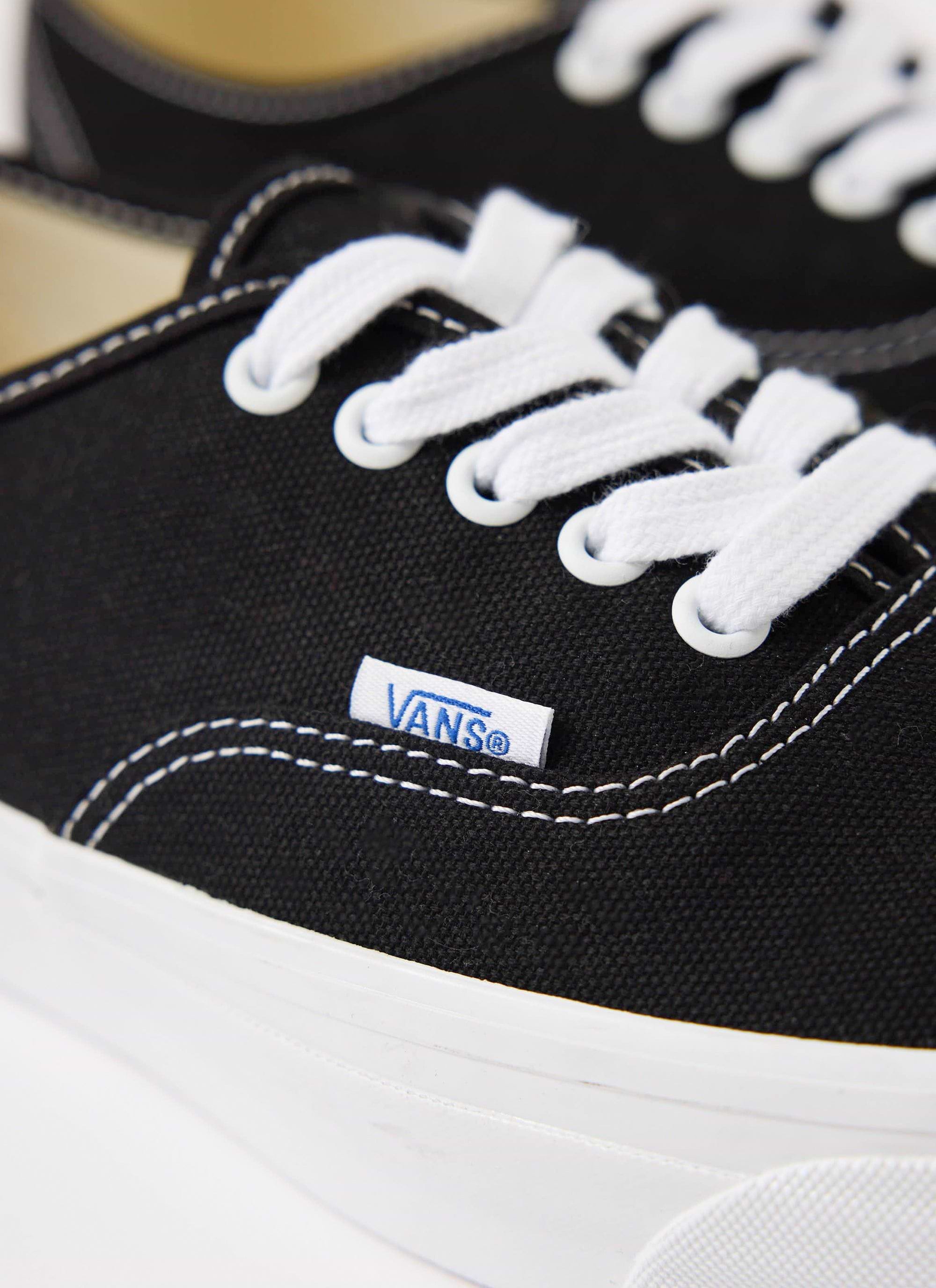 A close-up product shot of the black Vans Authentic 44 trainers, highlighting the white stitching and logo. From Percival.