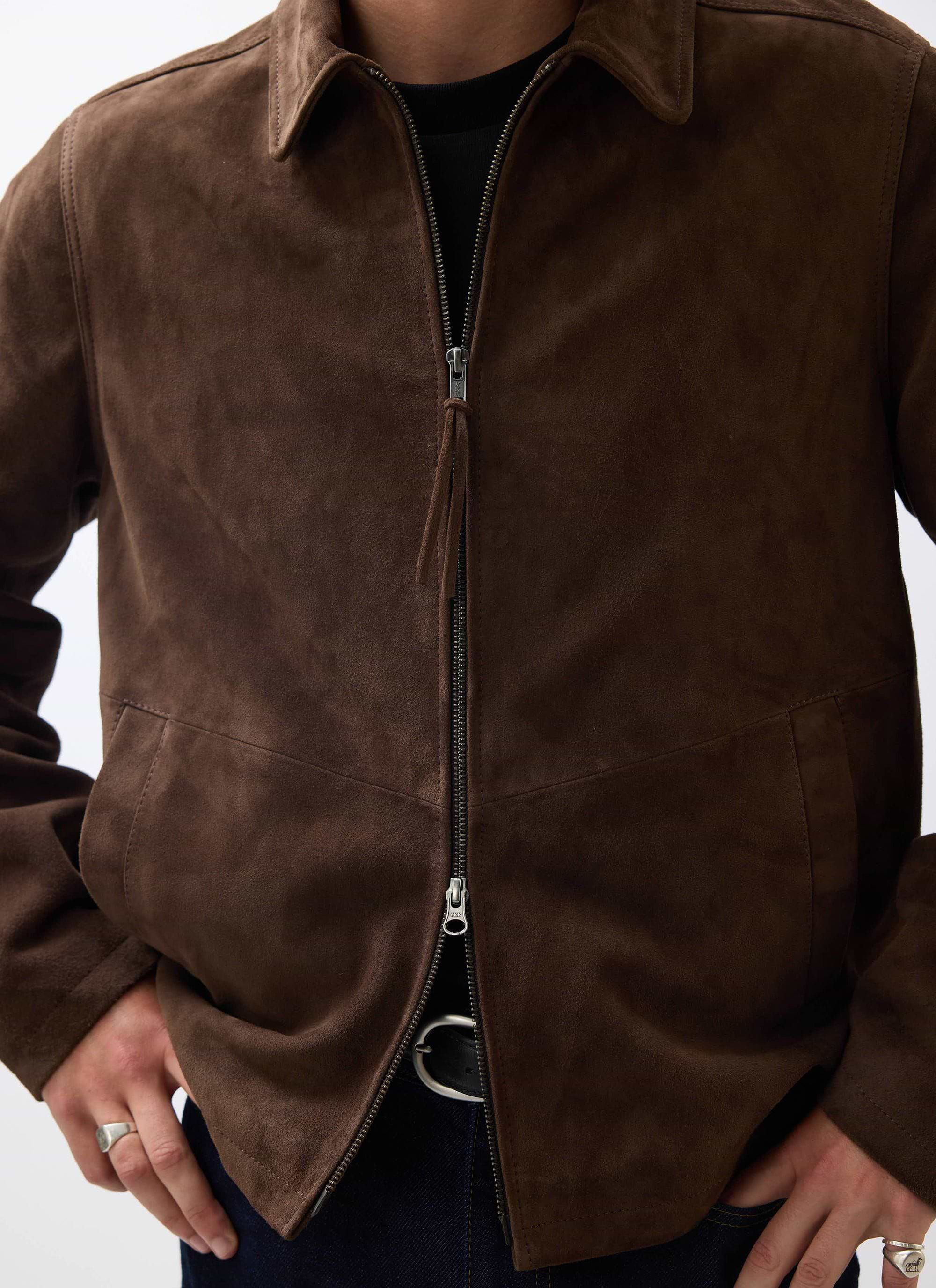 A close-up of a model wearing the Percival Prologue Soft Suede Jacket in espresso brown, showing its texture and zip detail.