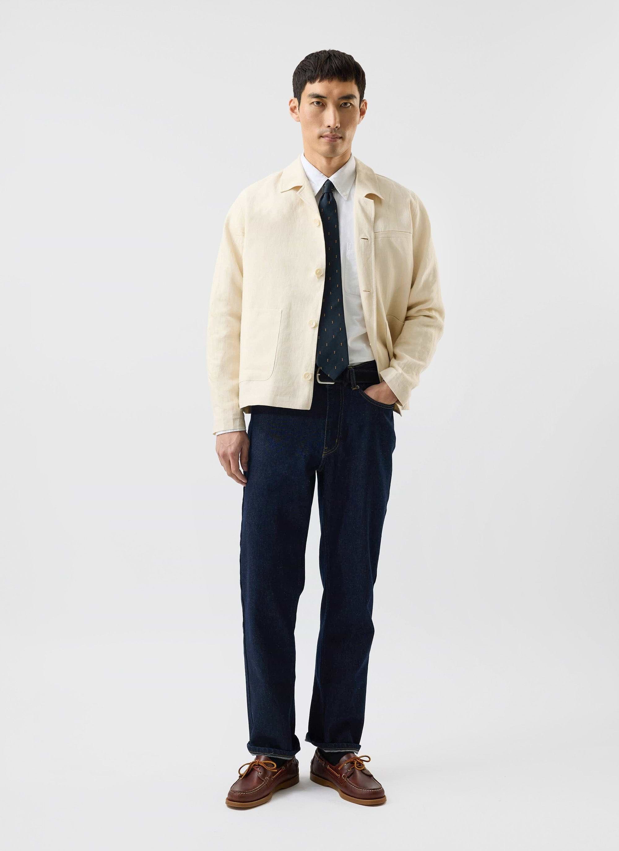 A model wears the Percival Relaxed Linen Overshirt in stone, styled with dark denim, a shirt and a tie.