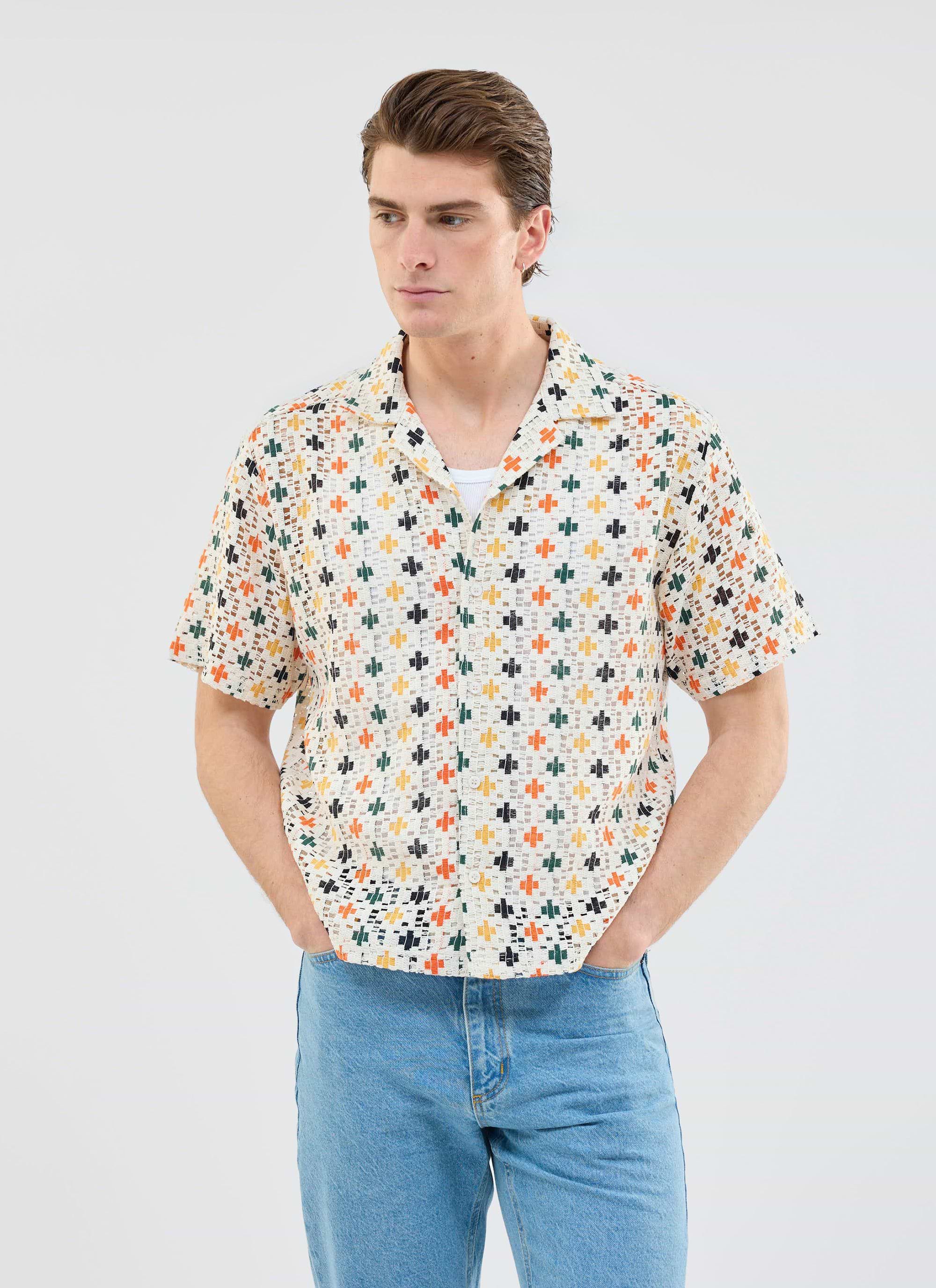 A model wears the multi-coloured Bailing Crochet Cuban Shirt from Percival, layered over a white t-shirt with blue jeans.