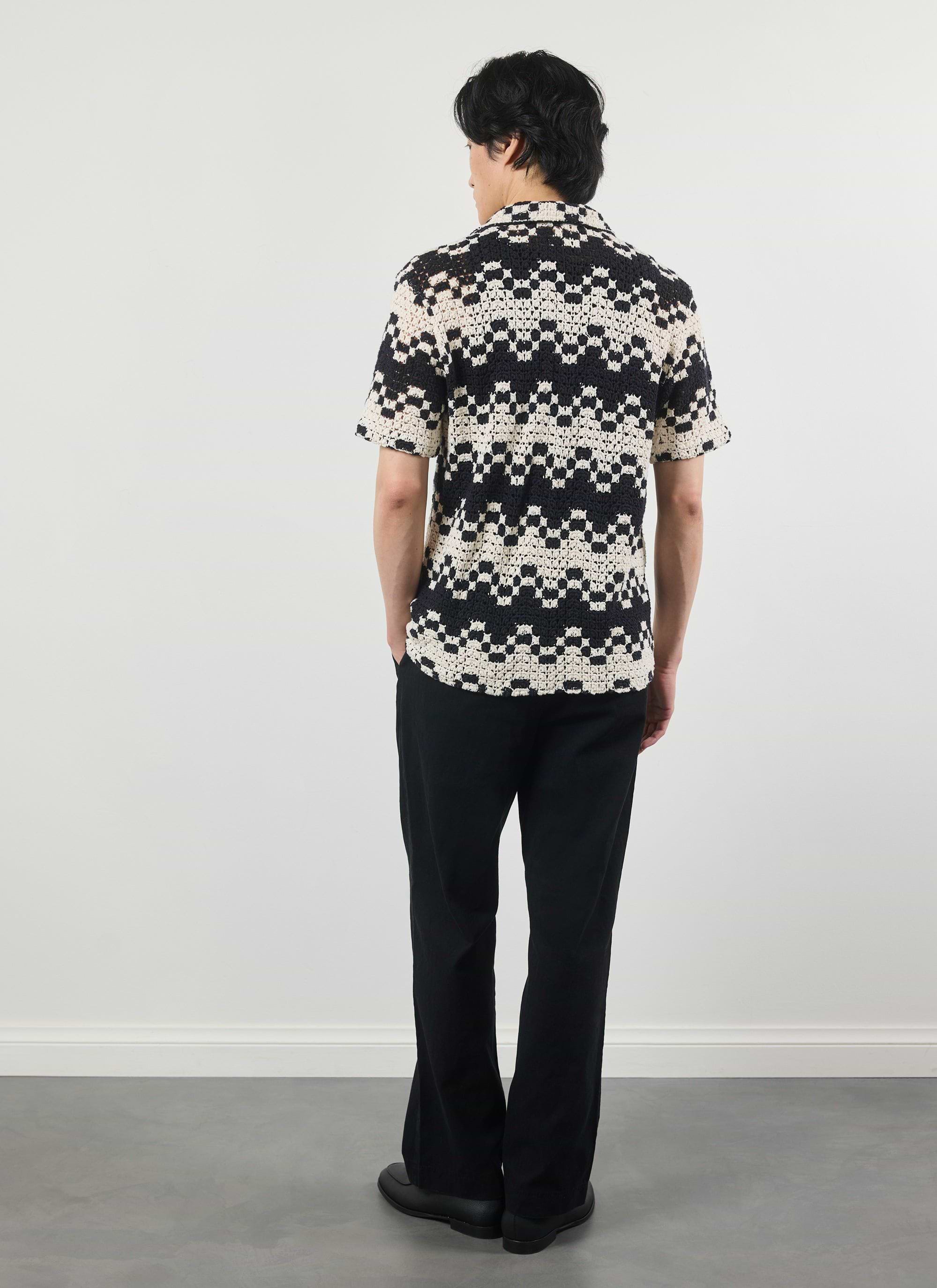 A model seen from behind wearing the Percival Naples Crochet Cuban Shirt, showing the intricate black and ecru pattern.