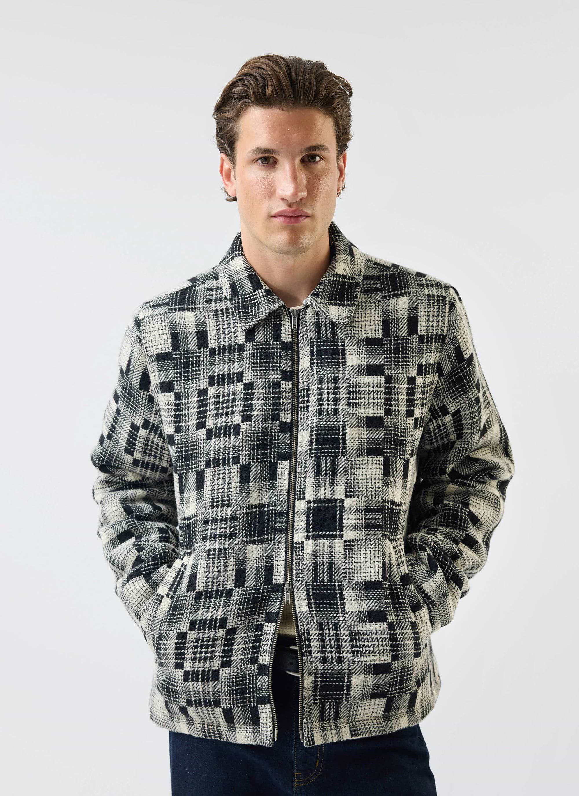 A model wears the Percival Glossary Patchwork Jacket in grey twill against a white studio background.