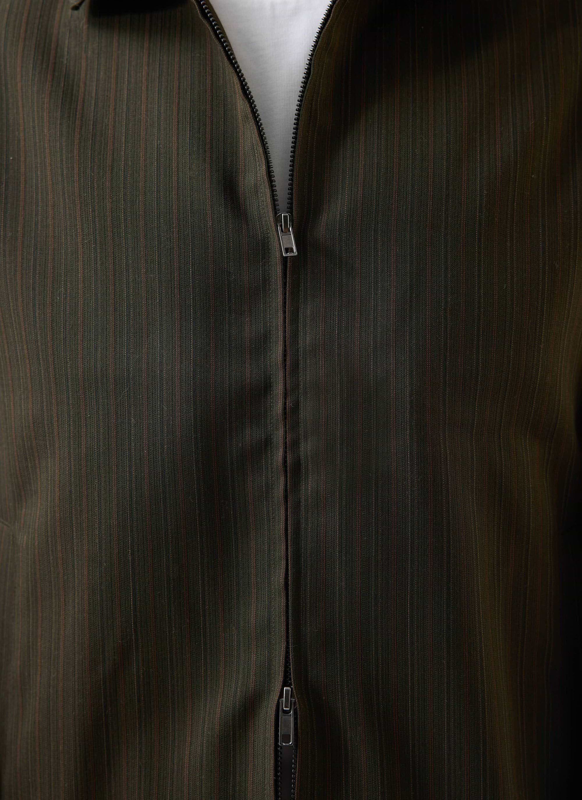 A close-up of the Percival Chapter Zip Up Jacket in forest green, showing the two-way zip and detailed twill fabric.