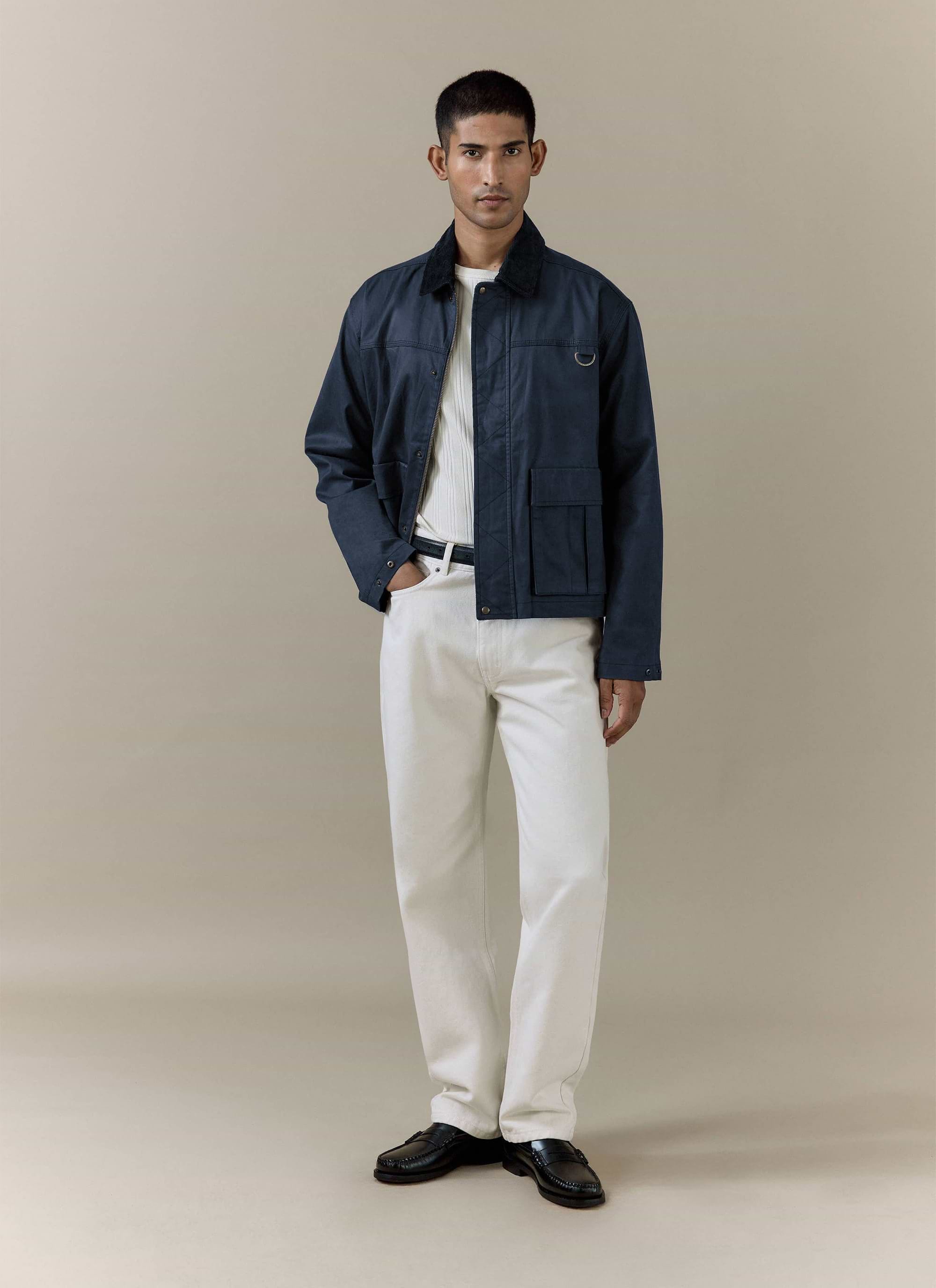 Navy blue Percival Wax Zip Jacket in waxed cotton, styled with white trousers and loafers in a studio shot.