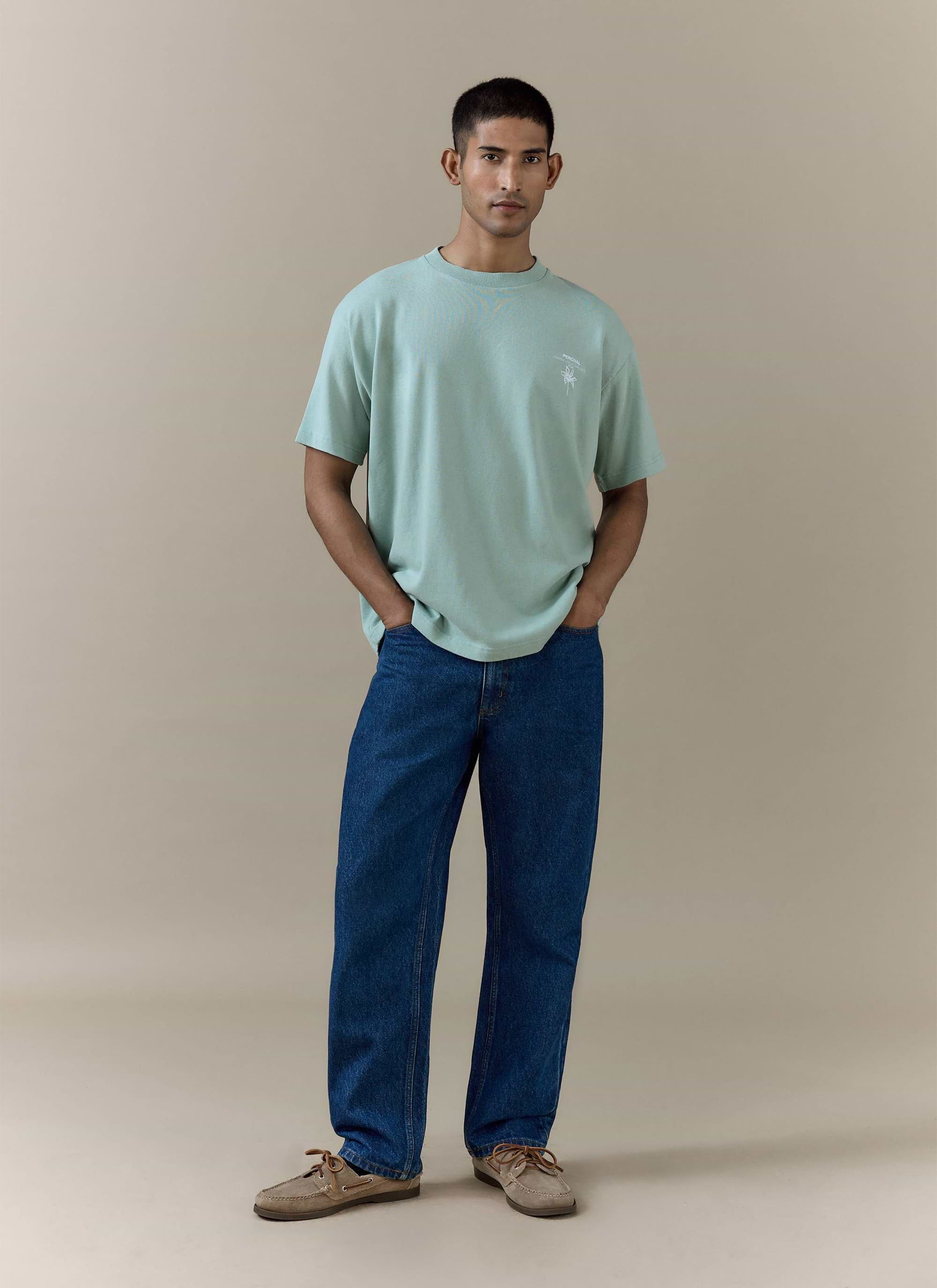Percival Melvin Oversized T Shirt in sage organic cotton, styled with blue denim jeans and brown boat shoes.