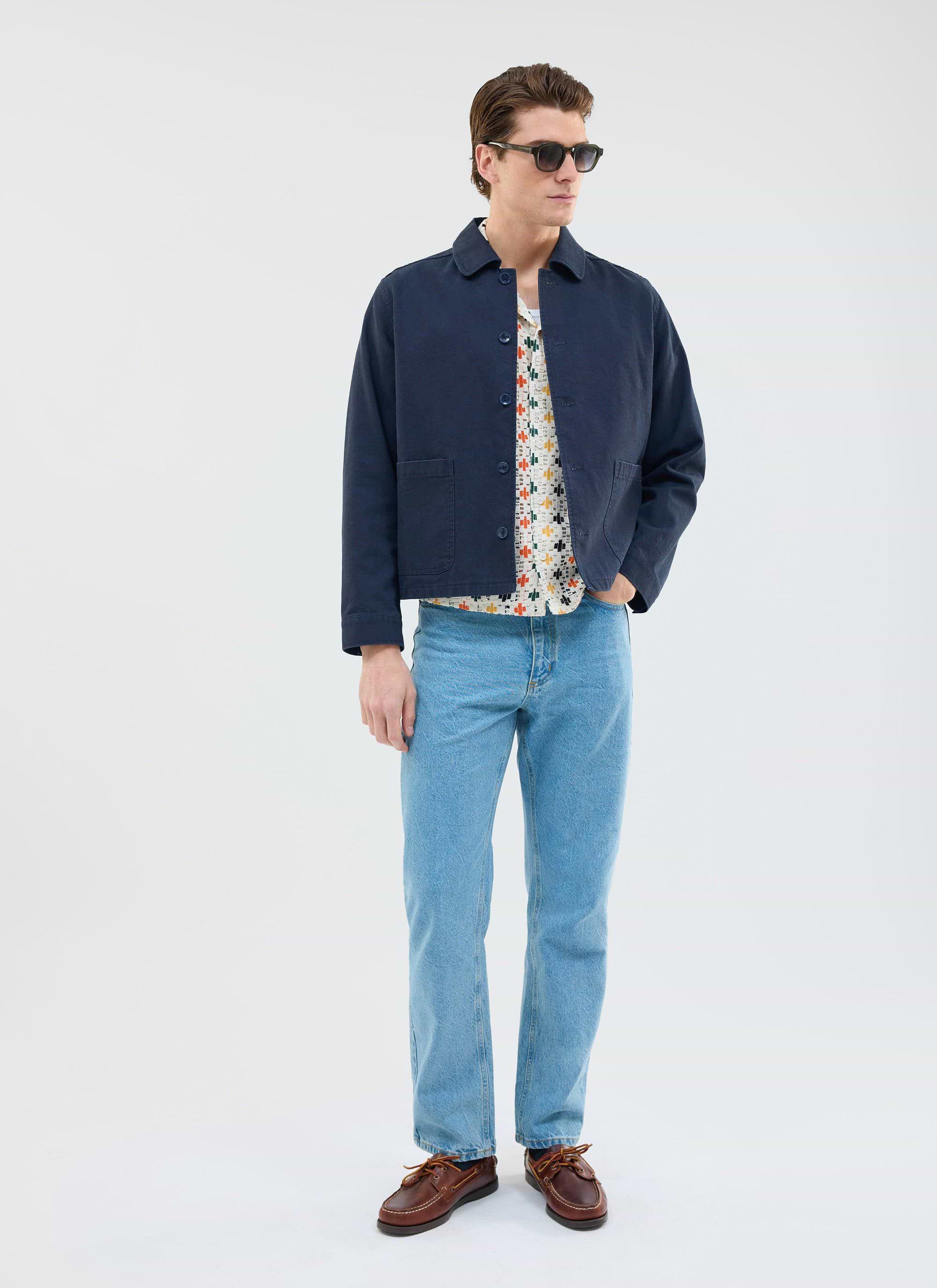 A model styles the Percival Bailing Crochet Cuban Shirt in multi, layered under a navy jacket with light wash blue jeans.