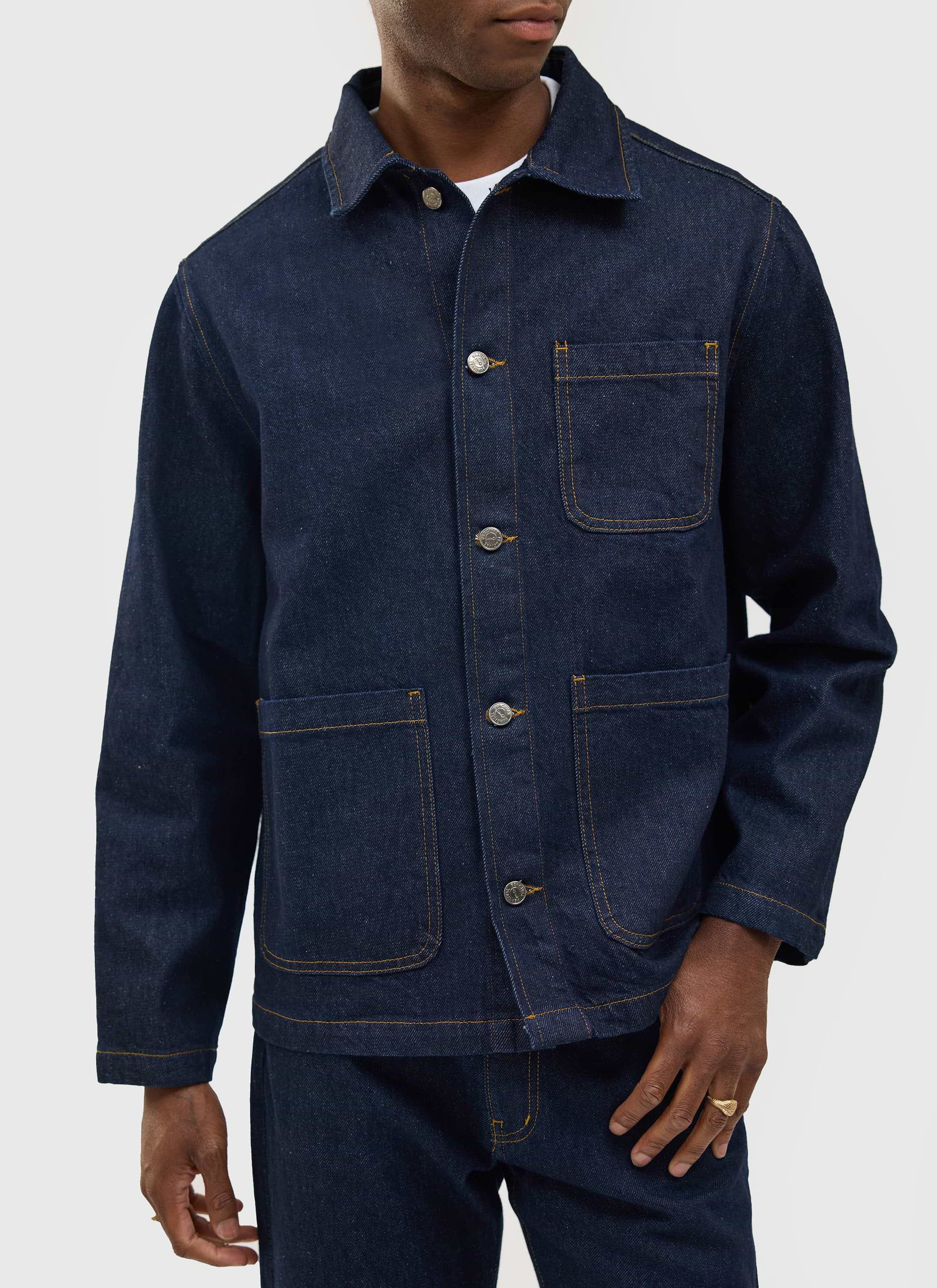 A model wears the Percival Gove Chore Jacket in dark indigo denim, highlighting its button front and patch pockets.
