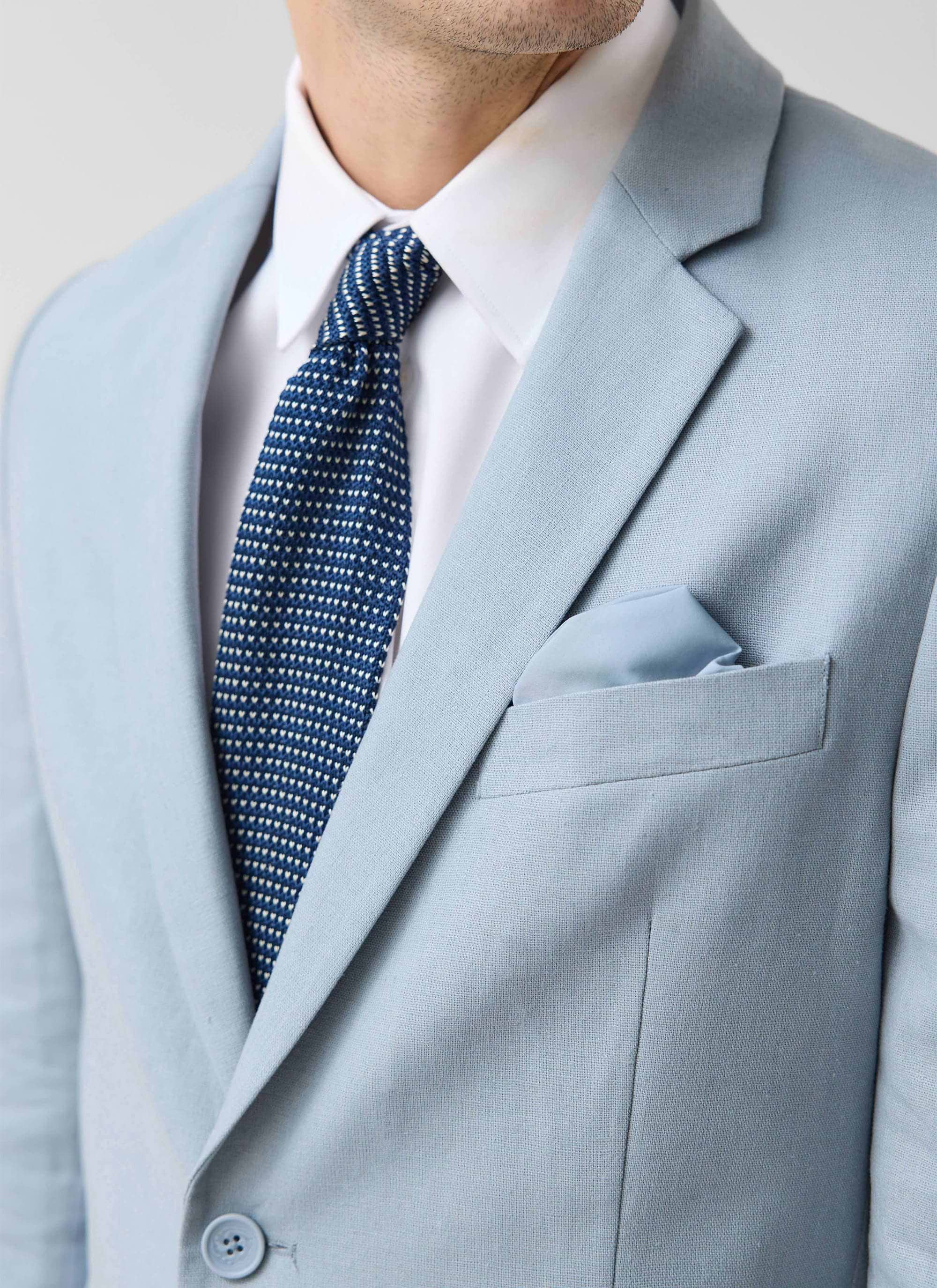 Close up of the Percival light blue tailored linen blazer with a white shirt and blue tie.