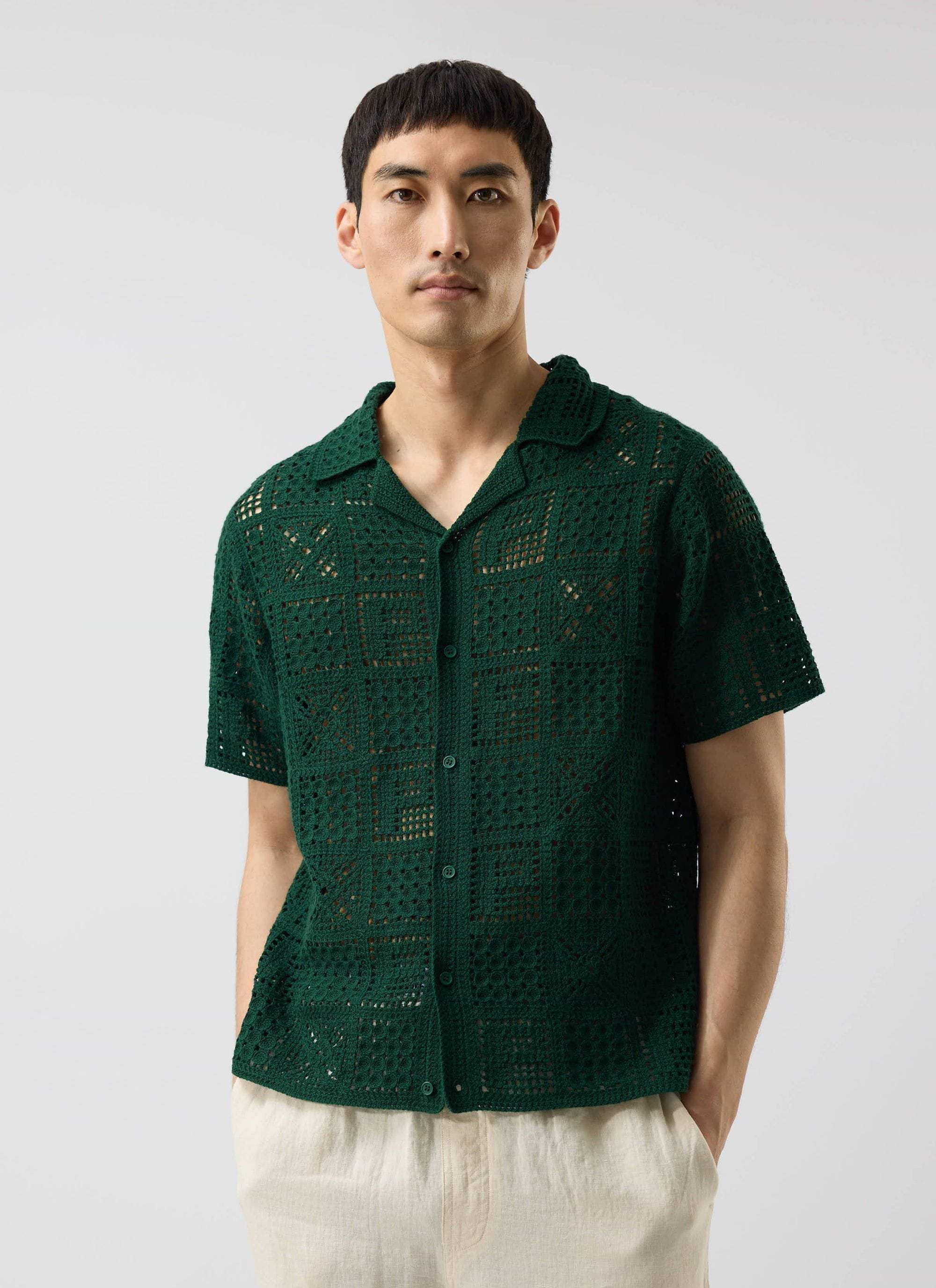 A model wears the Percival Crochet Groundsman Shirt in forest green, a short-sleeve button down with an open-knit design.
