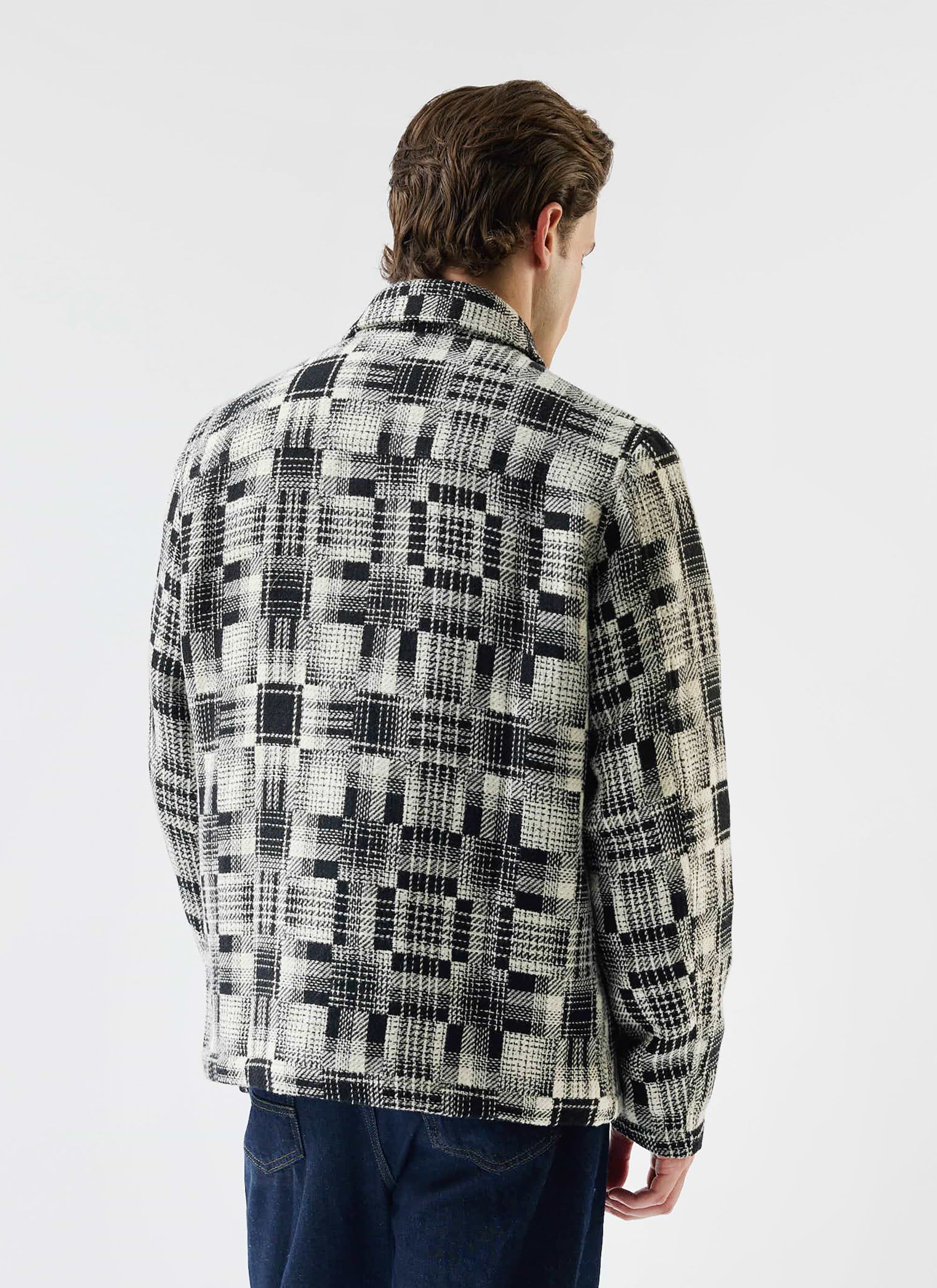 Rear view of a man modelling the grey twill Glossary Patchwork Jacket from Percival, showing the detailed pattern.