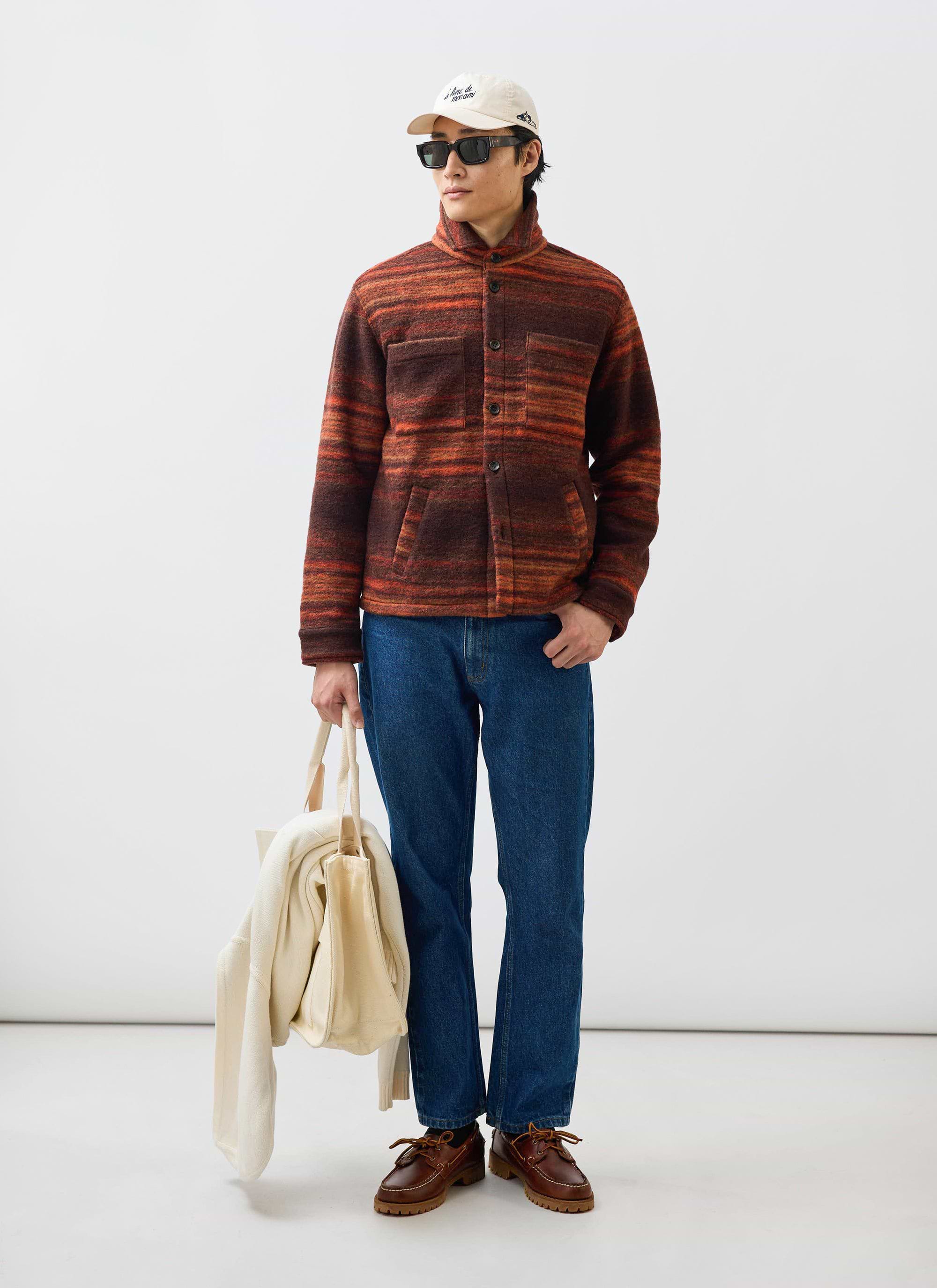 A man models the Percival Mississippi Jacquard Overshirt in burnt orange and brown, styled with blue jeans and sunglasses.