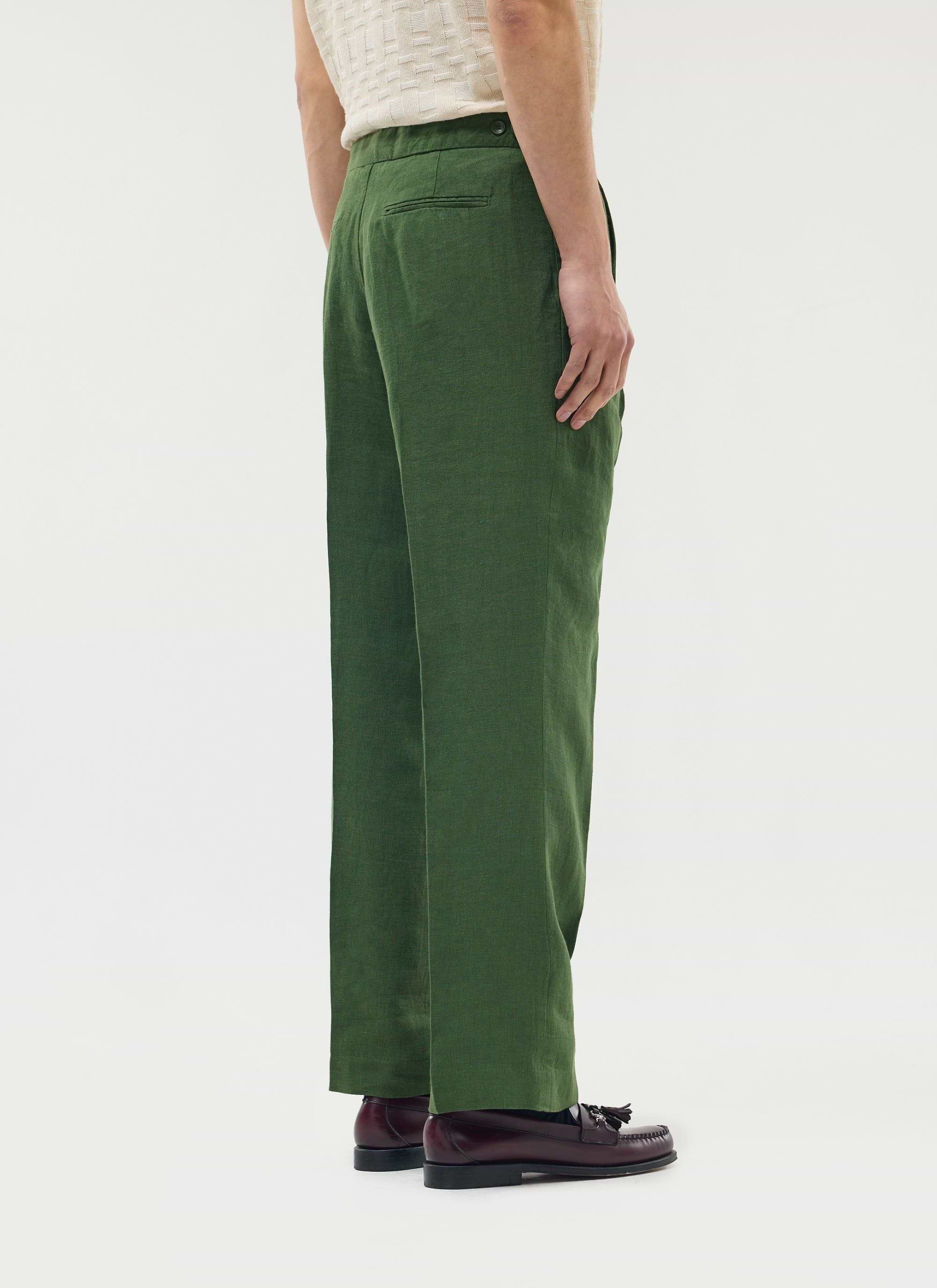 A model wears the Percival Pleated Tailored Trousers in Forest green linen, shot from behind on a white background.