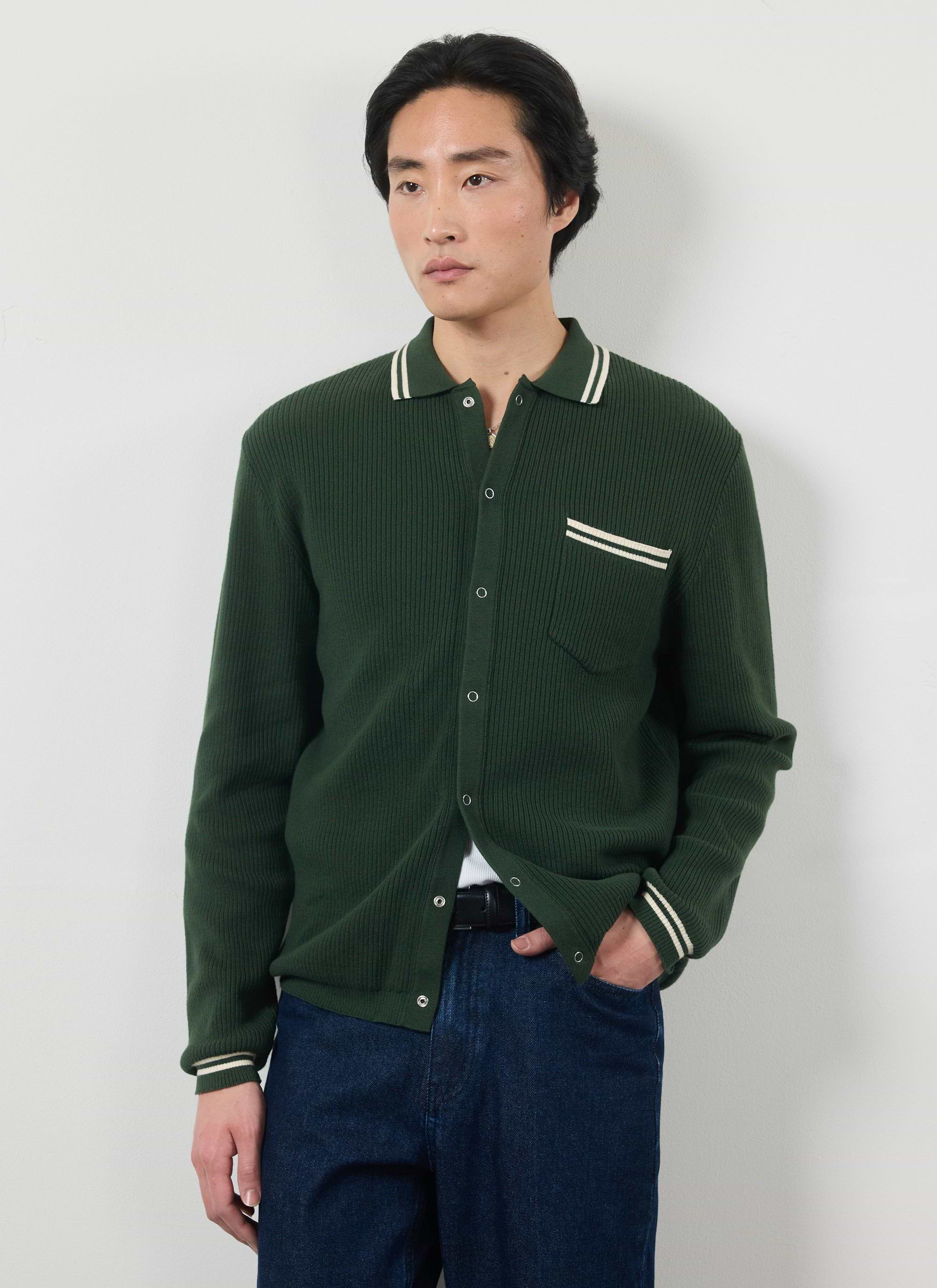 Model wears the Percival Pablo long sleeve knitted shirt in forest green with white stripes on the collar, pocket, and cuffs.