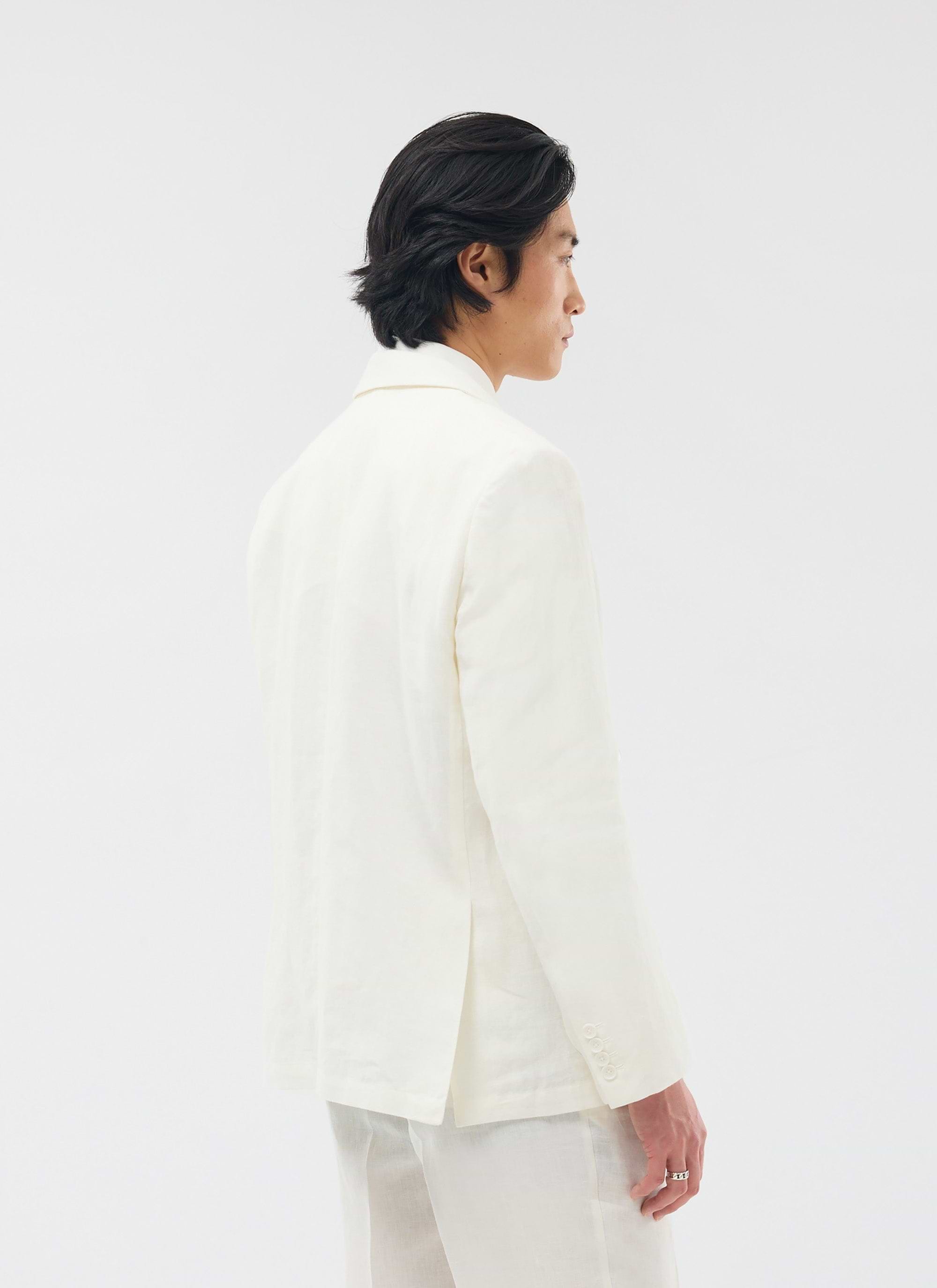 A model with dark hair wears the Percival Relaxed Tailored Linen Blazer in white, shown from a three-quarter back view.