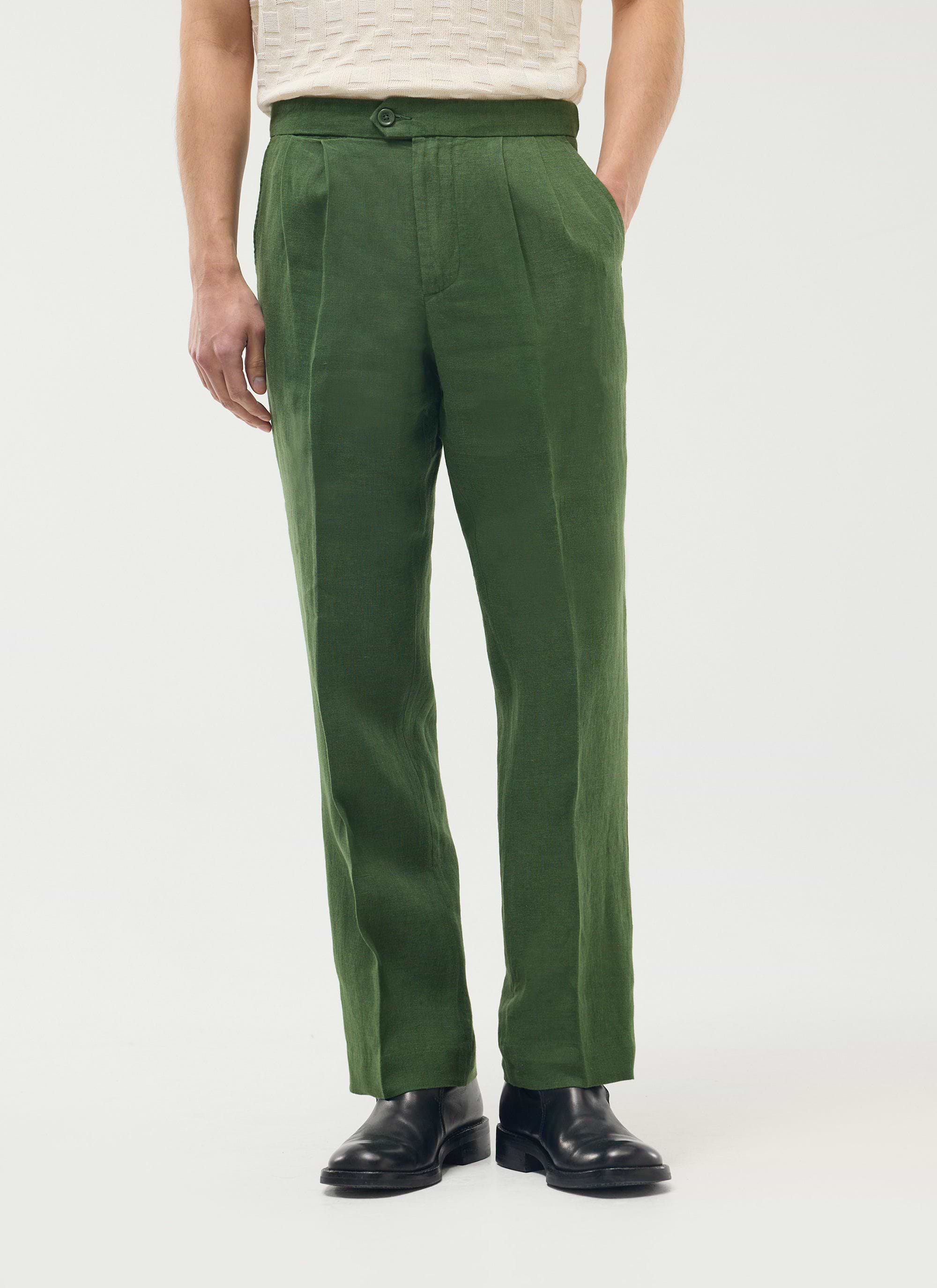 A model wears the Percival Pleated Tailored Trousers in forest green linen with a cream top and black shoes.