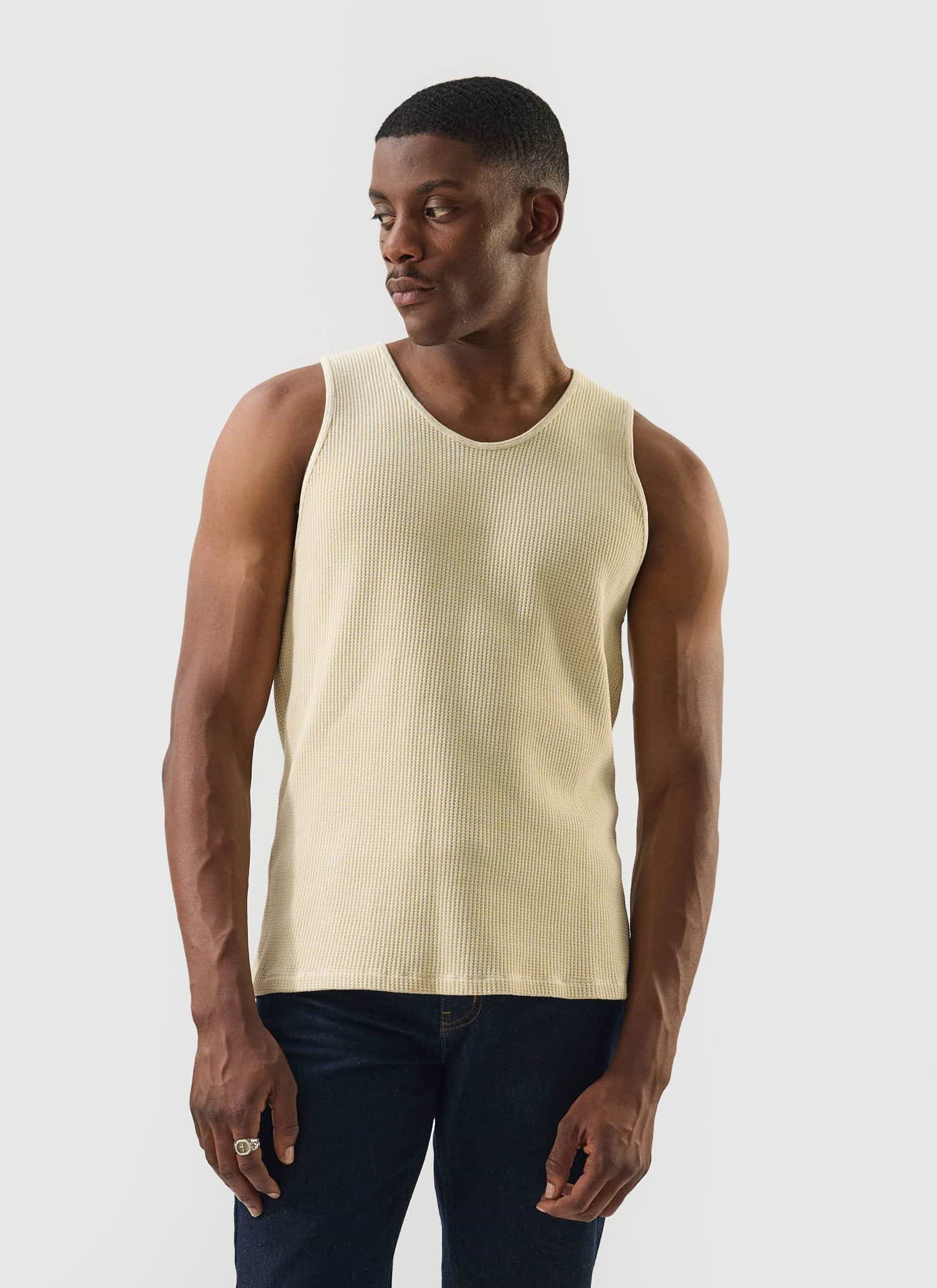 A model wears the Percival Cotton Waffle Vest in ecru with dark jeans, styled against a simple white background.