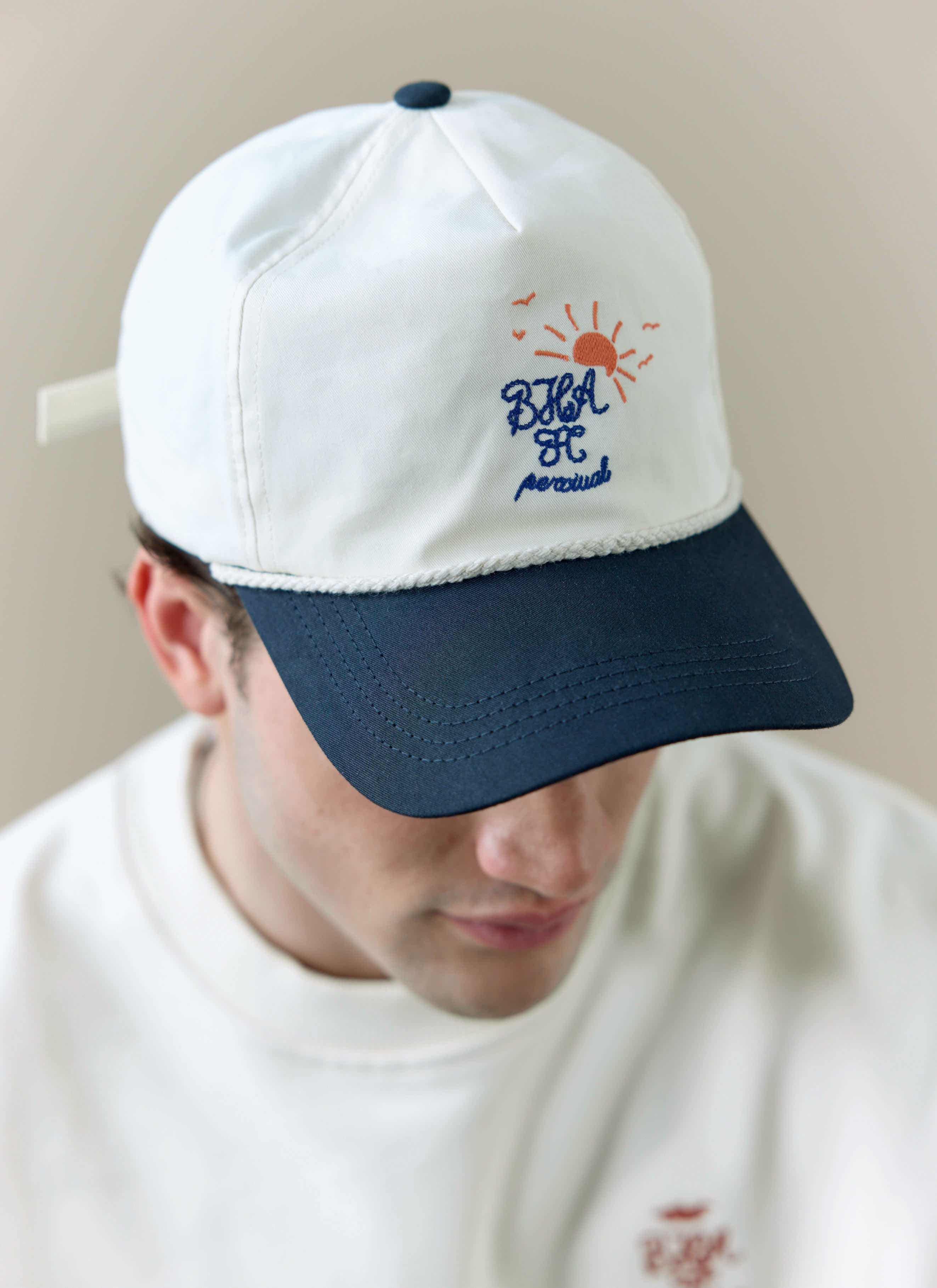 A close-up of a model wearing the cream and navy Trucker Cap from the Percival x Brighton & Hove Albion F.C. collaboration.