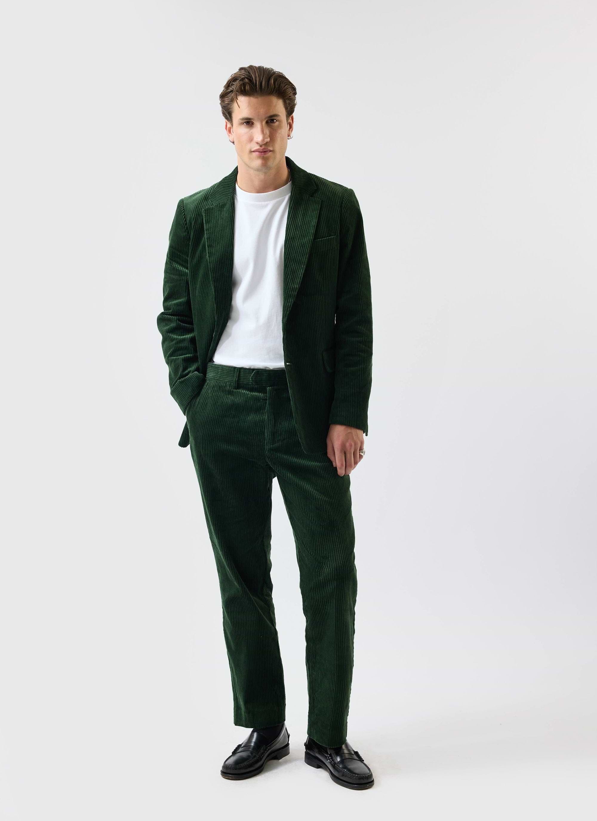 A model poses in the Percival forest green chunky cord suit, styled casually with a white t-shirt and black loafers.