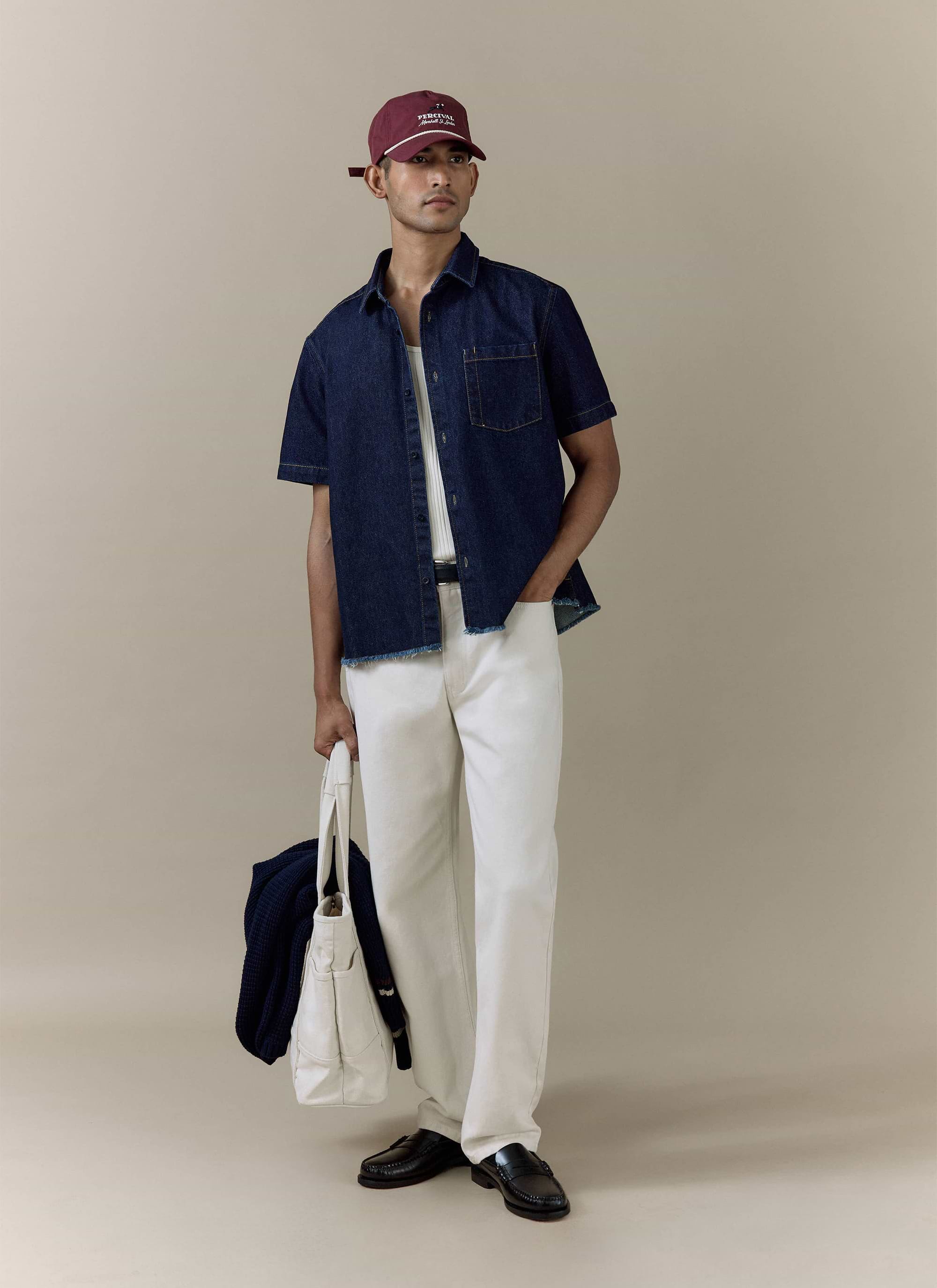 Percival Harley Denim Cropped Boxy Shirt in dark indigo cotton, styled with white trousers and a burgundy cap.