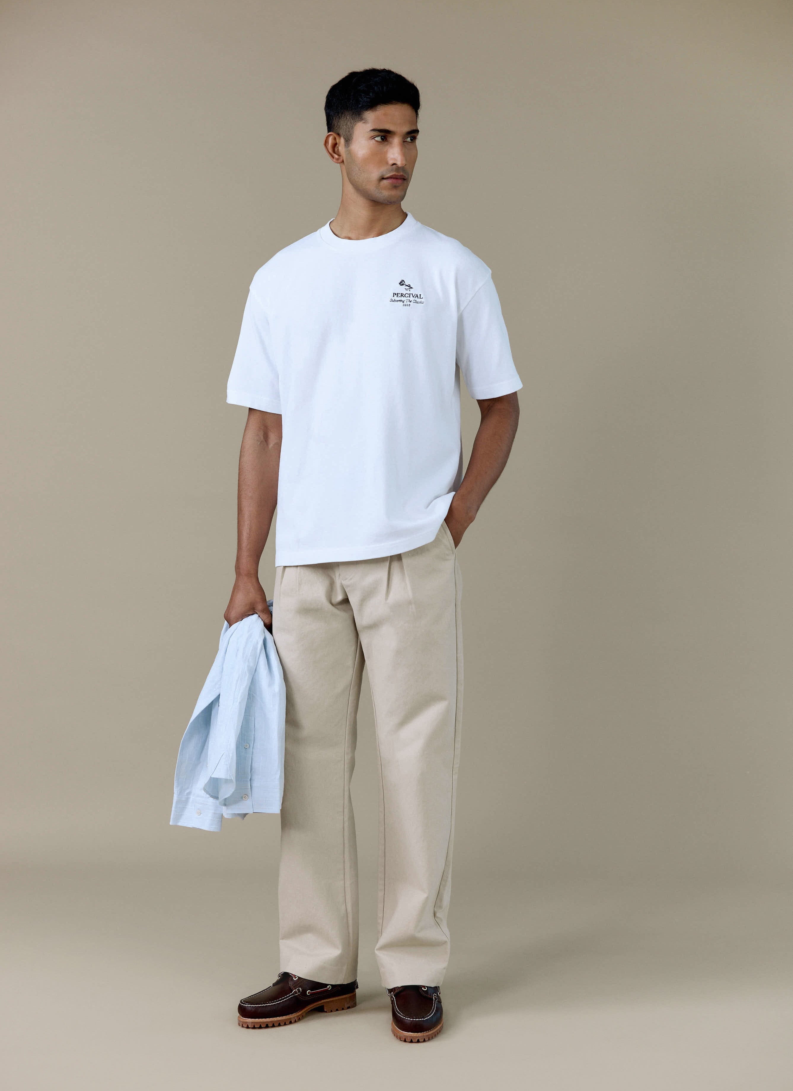 A model wearing the white Percival Perci Waters Oversized T Shirt in organic cotton, styled with beige trousers.