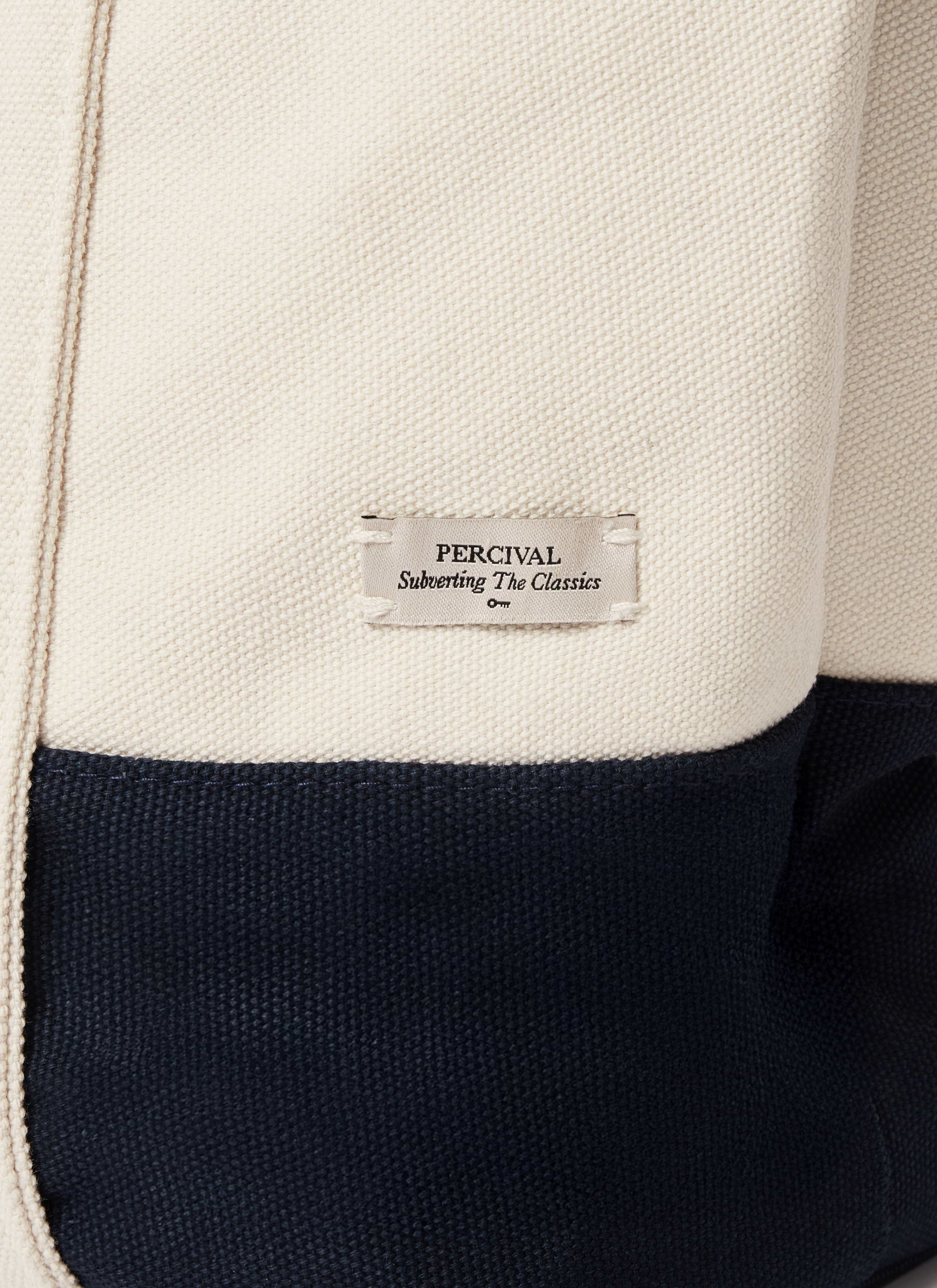 A close-up of the Percival woven label on the navy and cream Brighton & Hove Albion F.C. canvas tote bag.