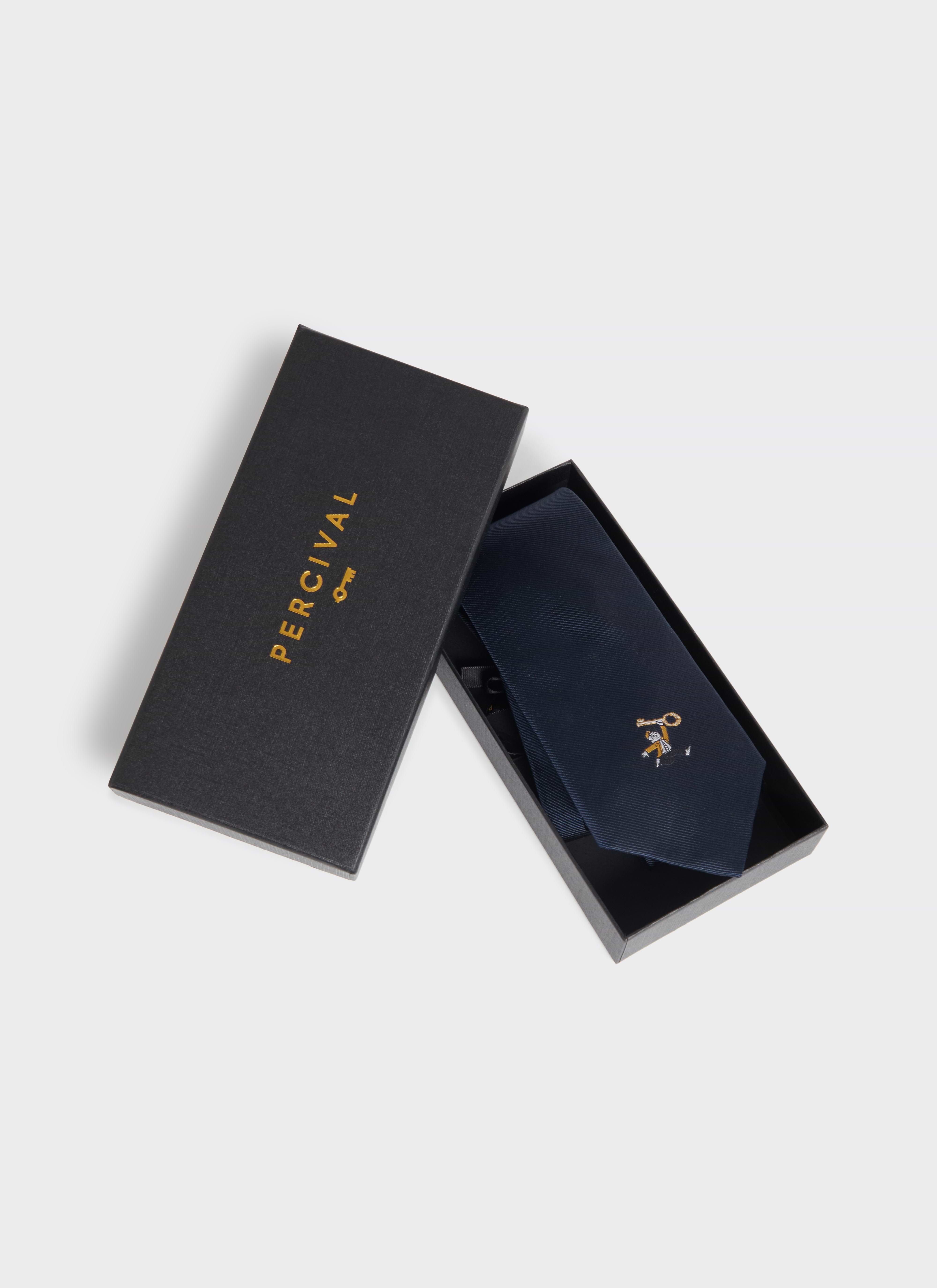 Navy silk Percival World Key Tie with embroidered motif, displayed in a black branded gift box.