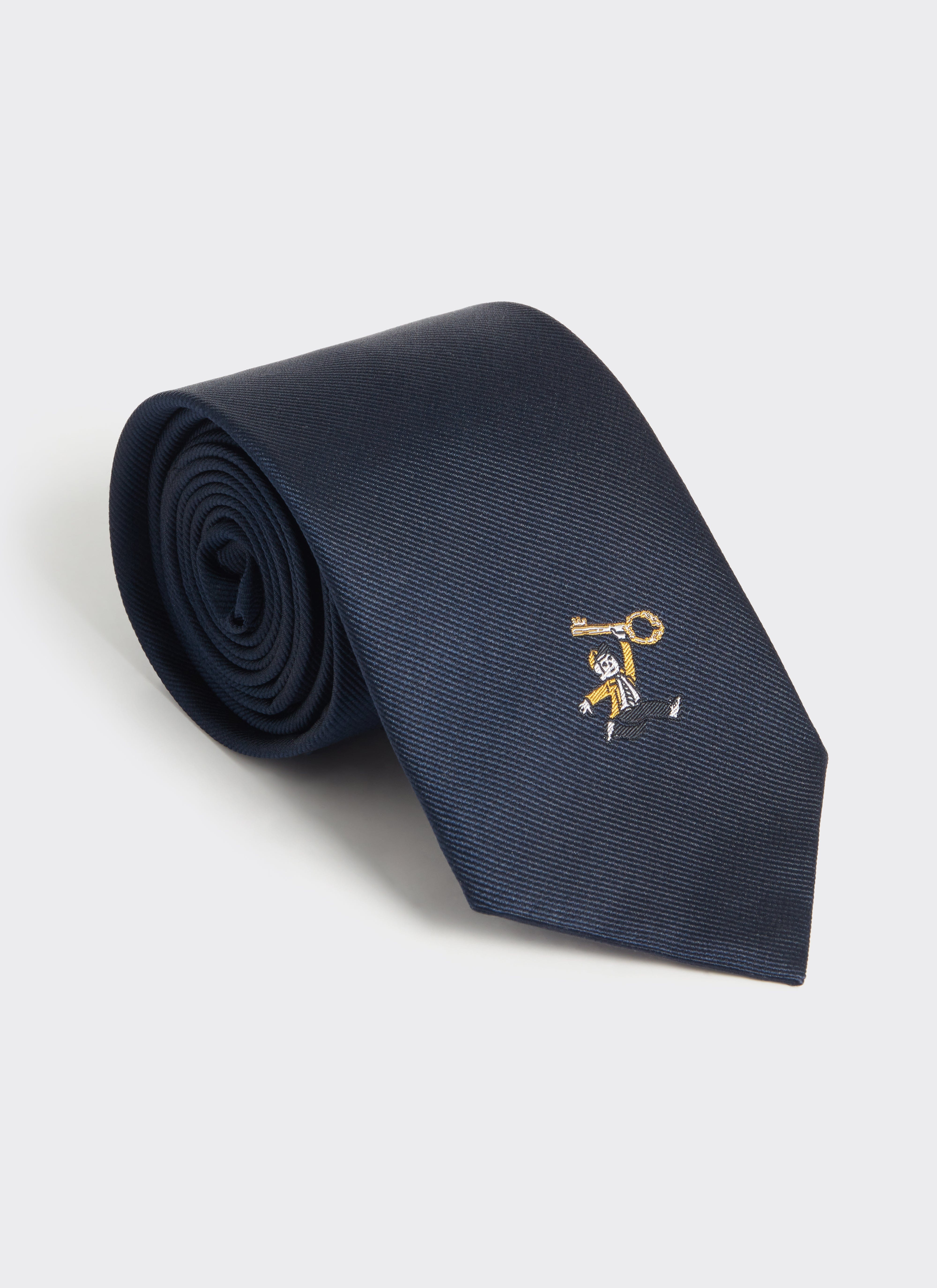 Navy 100% silk World Key Tie by Percival, rolled to display the embroidered character and key motif.
