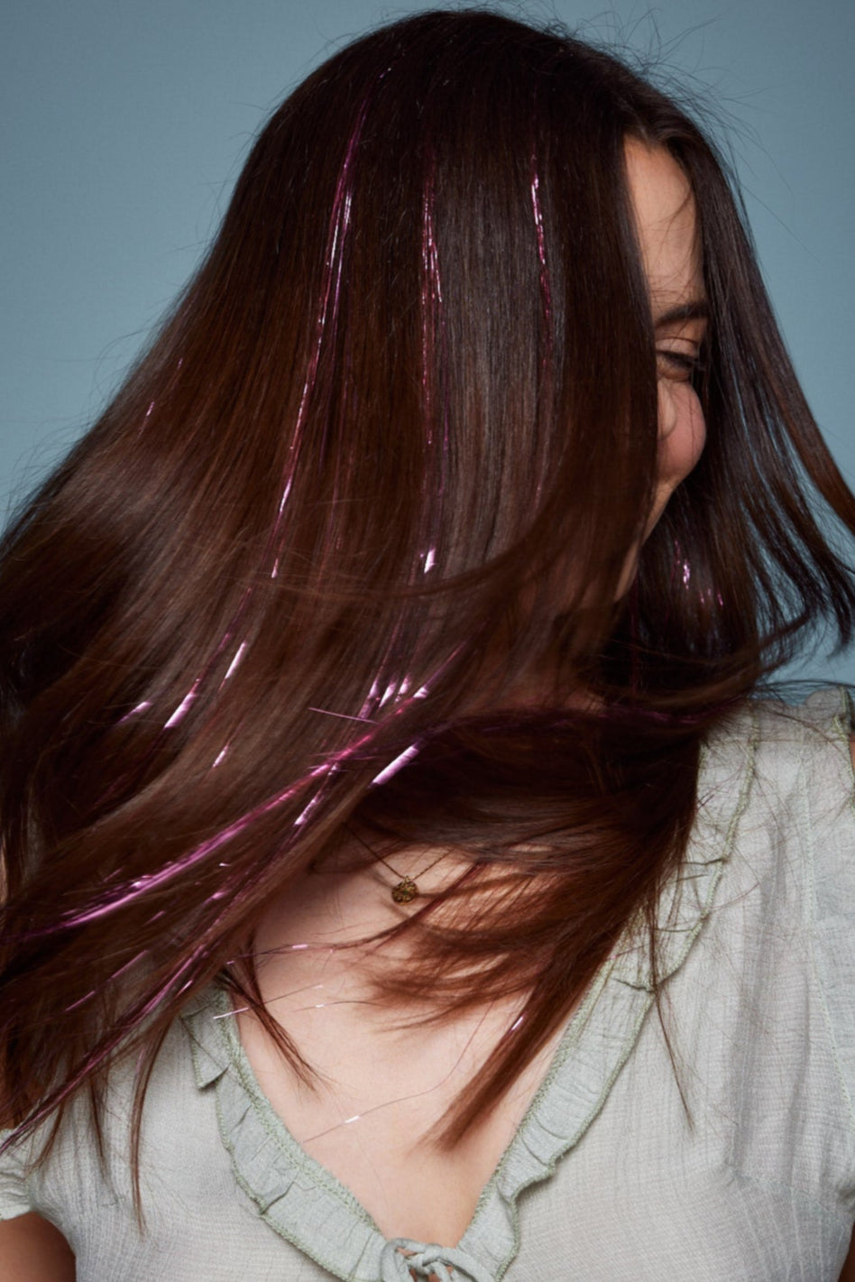 קלוז אפ של בחורה שבשיער שלה שזורים חוטי טינסל בצבעי ורוד זוהר - הנקראים אצלנו גווני פיות. מיועדים לחיבור עצמאי, פשוט וקבוע לשיער או לחיבור זמני - Shufizoo