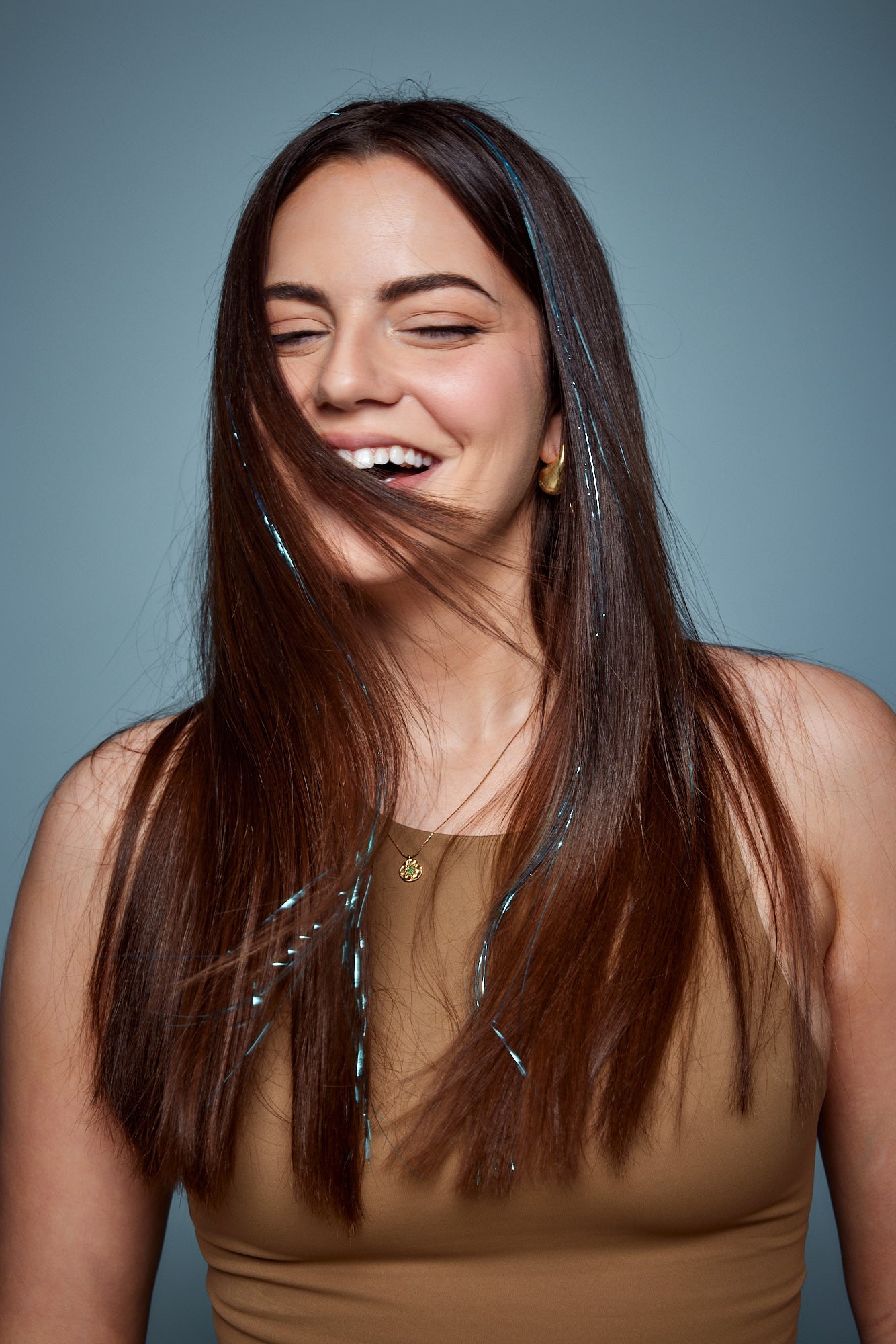 מדיום שוט של בחורה שבשיער שלה שזורים חוטי טינסל בצבעי כחול בהיר זוהר - הנקראים אצלנו גווני פיות. מיועדים לחיבור עצמאי, פשוט וקבוע לשיער או לחיבור זמני - Shufizoo