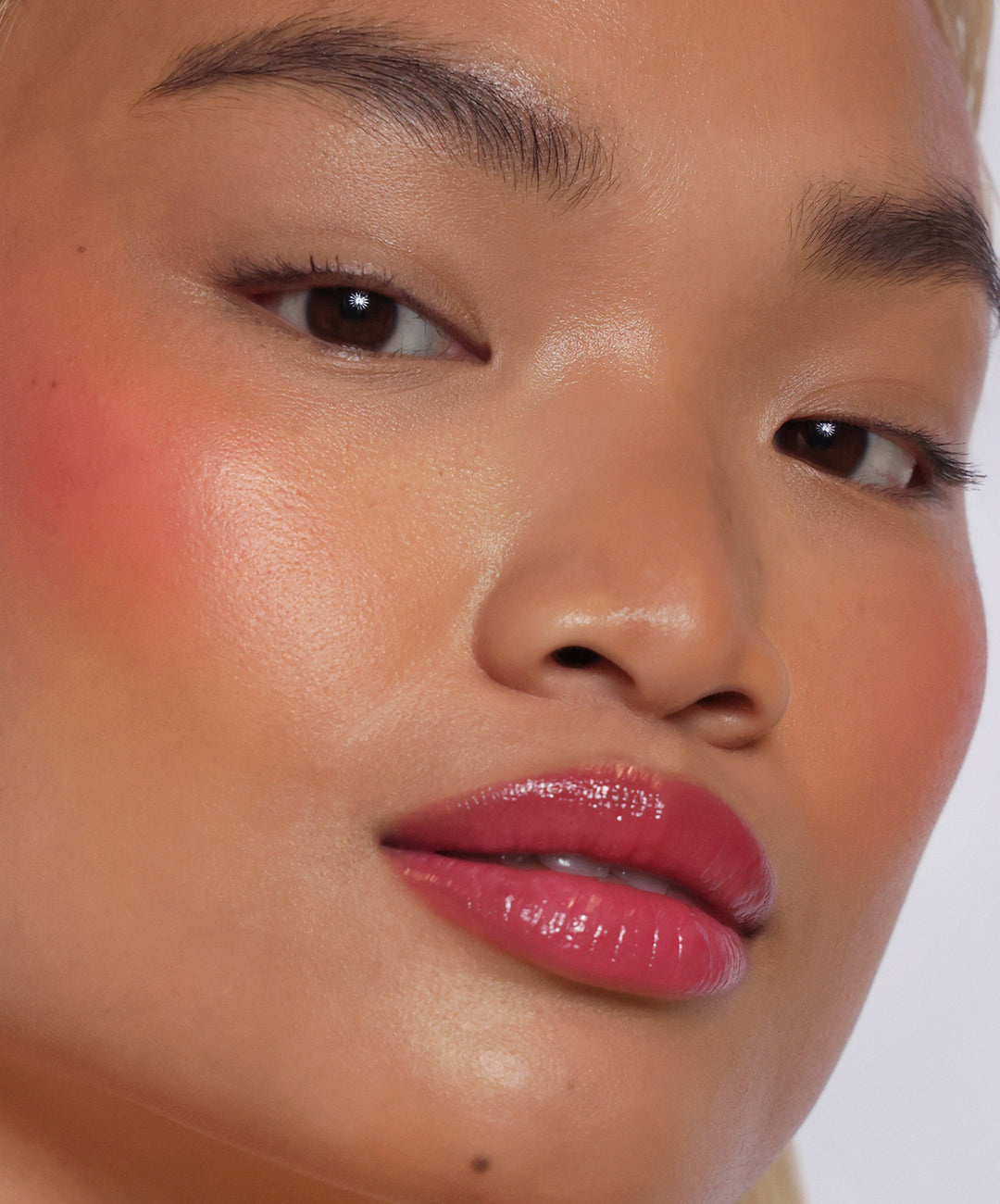 | desc: Model wears Lip Gloss in shade Guava