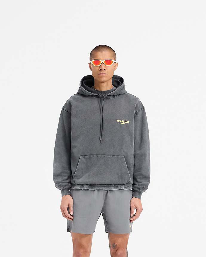 Man wearing an oversized grey hoodie with yellow print on a plain white background | Team 247 Oversized Hoodie in Pewter Lemon | Oversized fit hoodie with ribbed cuffs and hem | 247 Hoodies | Represent Clo