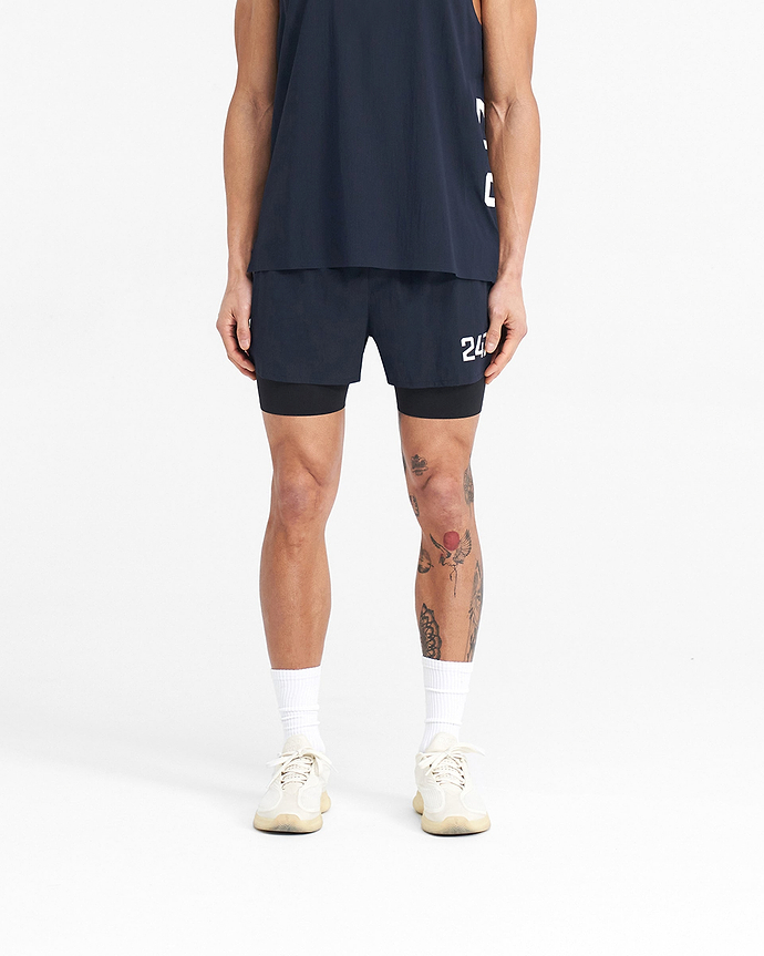 Man wearing navy shorts on a plain white background | 247 Trail Short in Navy | 2-in-1 trail shorts with 4-way stretch and internal tight | 247 Shorts | Represent Clo
