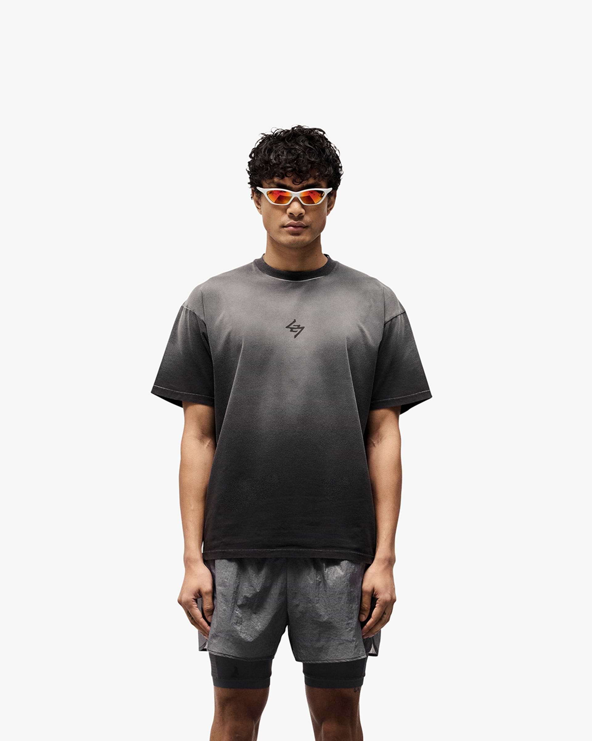 Man wearing an oversized black t-shirt with graphic print on a plain white background | 247 Motion Oversized T-Shirt in Aged Black | Oversized t-shirt with sweat wicking and antibacterial properties | 247 T-Shirts | Represent Clo